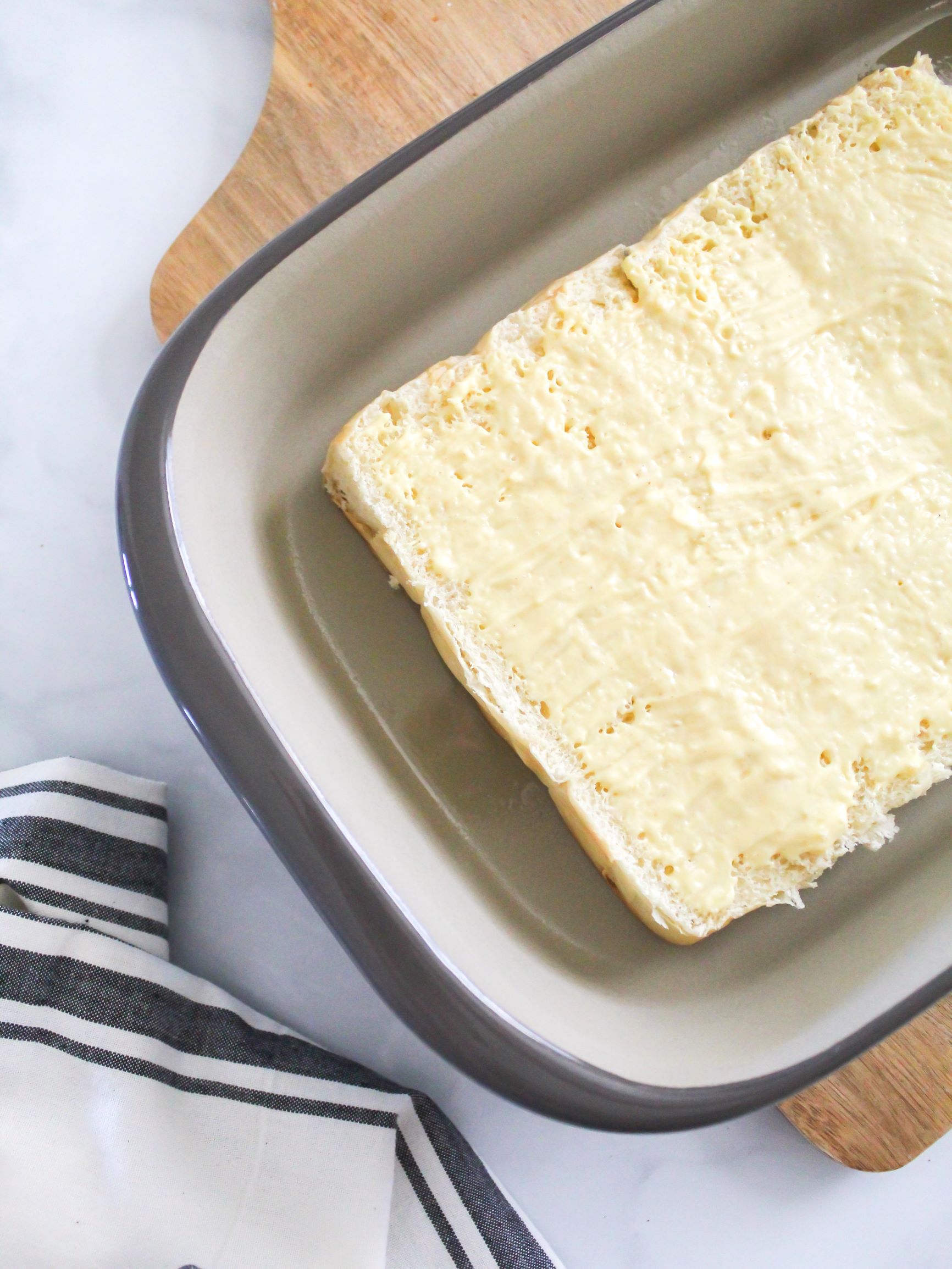 Spreading honey mustard sauce on bottom layer of sweet Hawaiian roles to make turkey and provolone sliders