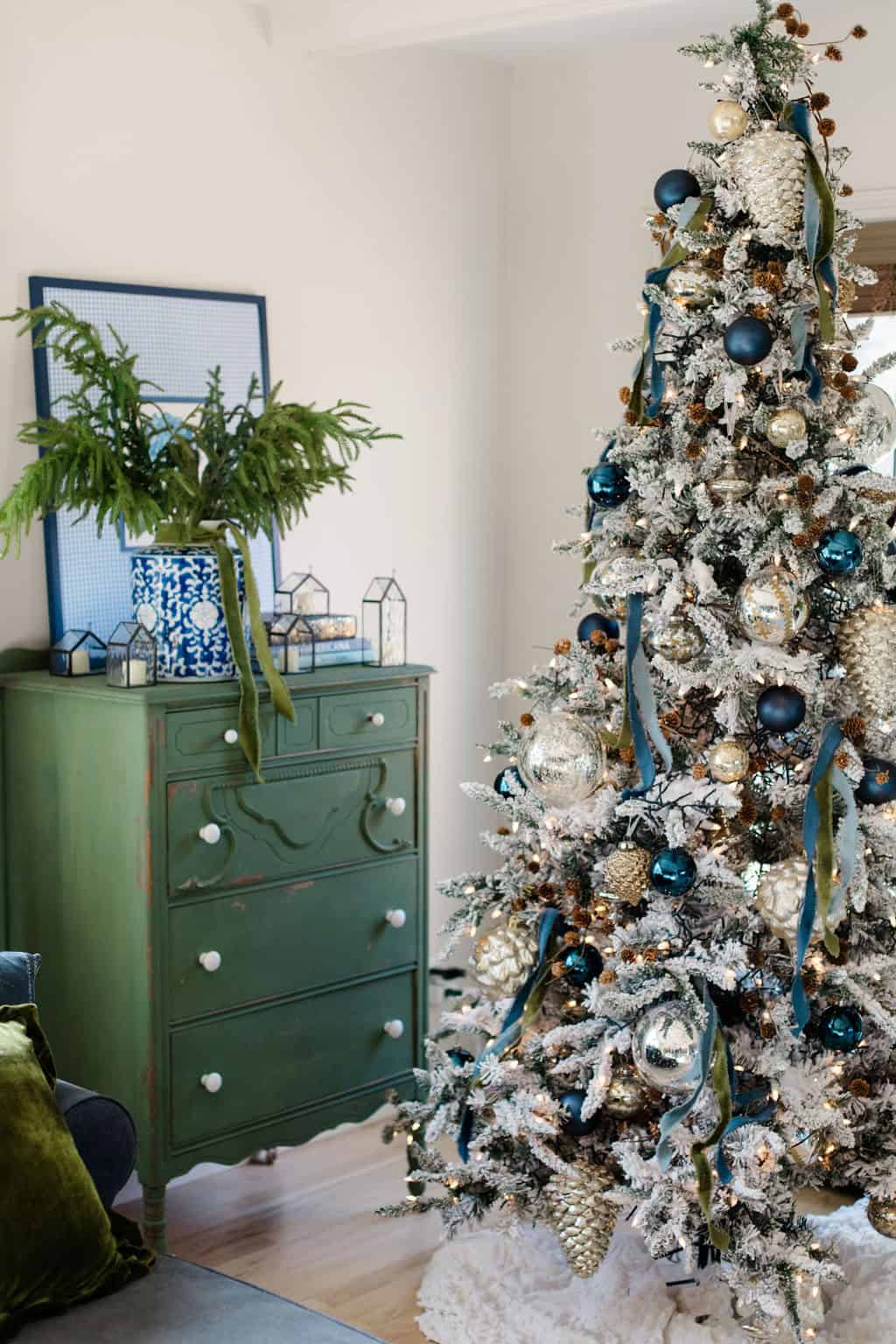 Flocked Christmas tree decoratedd using  blue and silver ornaments with green velevet bows