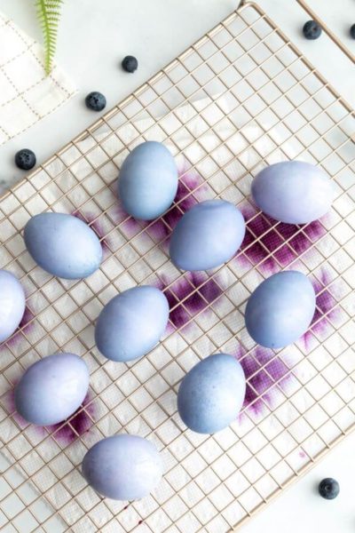 Natural blueberry dyed hard boiled Easter eggs drip drying on a wire rack