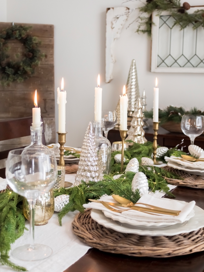 Cozy Christmas dining table with candles and greenery.