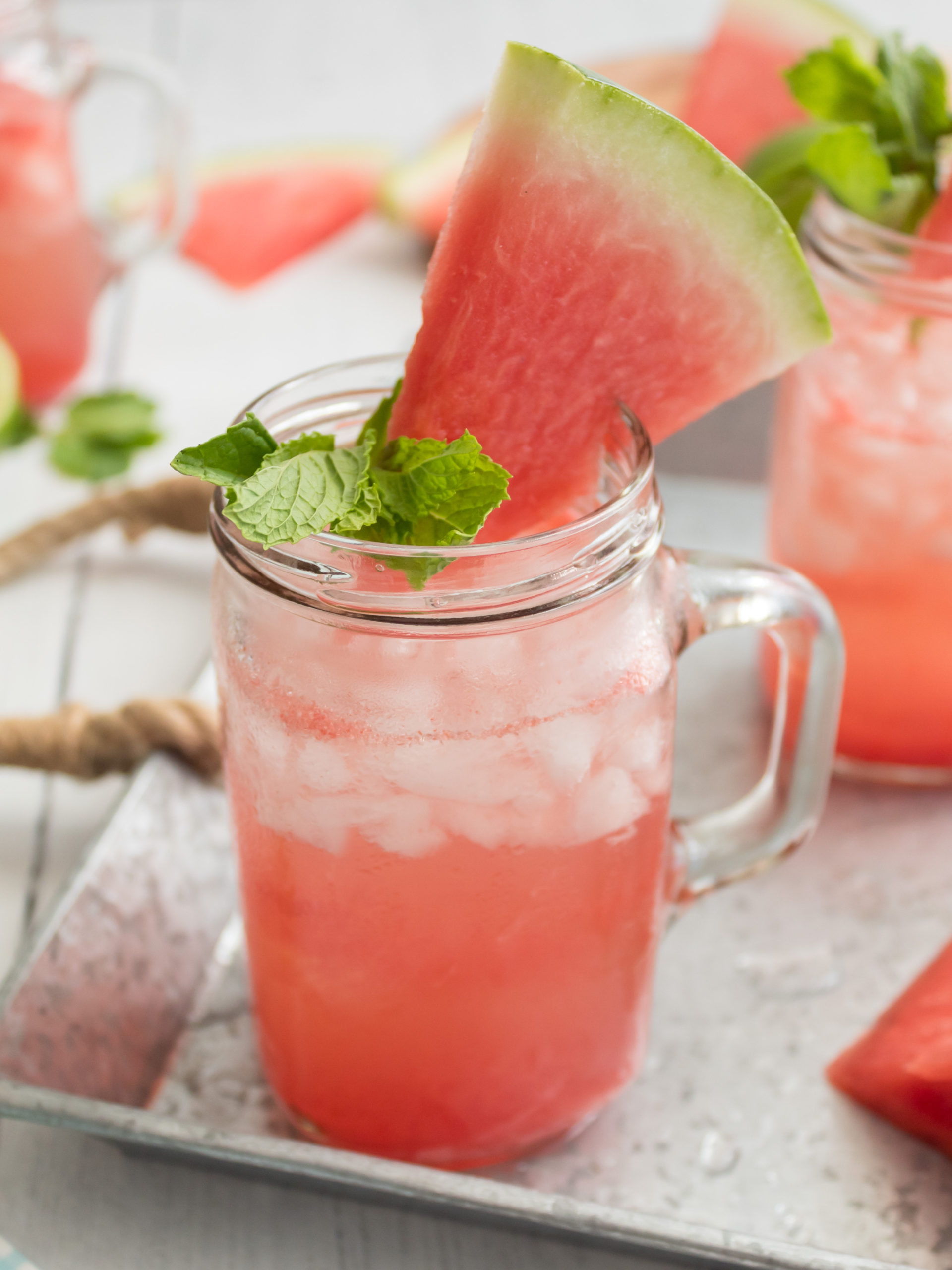 Watermelon crush cocktail served in a mason jar glass with a watermelon wedge and mint sprig garnish