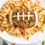 Close-up of a Jalapeño Popper Cheese Ball shaped like a football with cheese football "laces" showing bacon, jalapeños, and creamy cheese