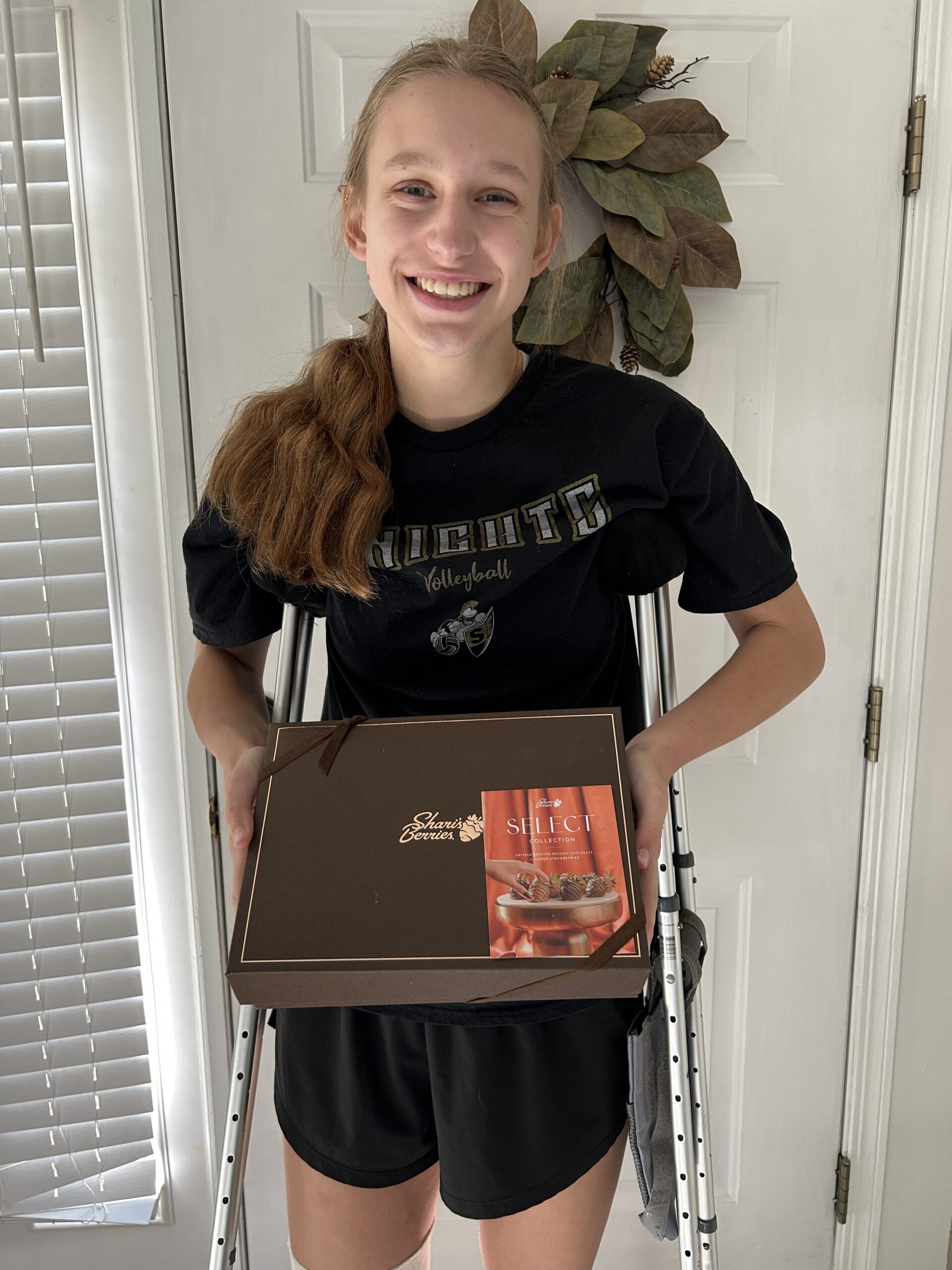 girl smiling on crutches holding a box of sherrie's berries