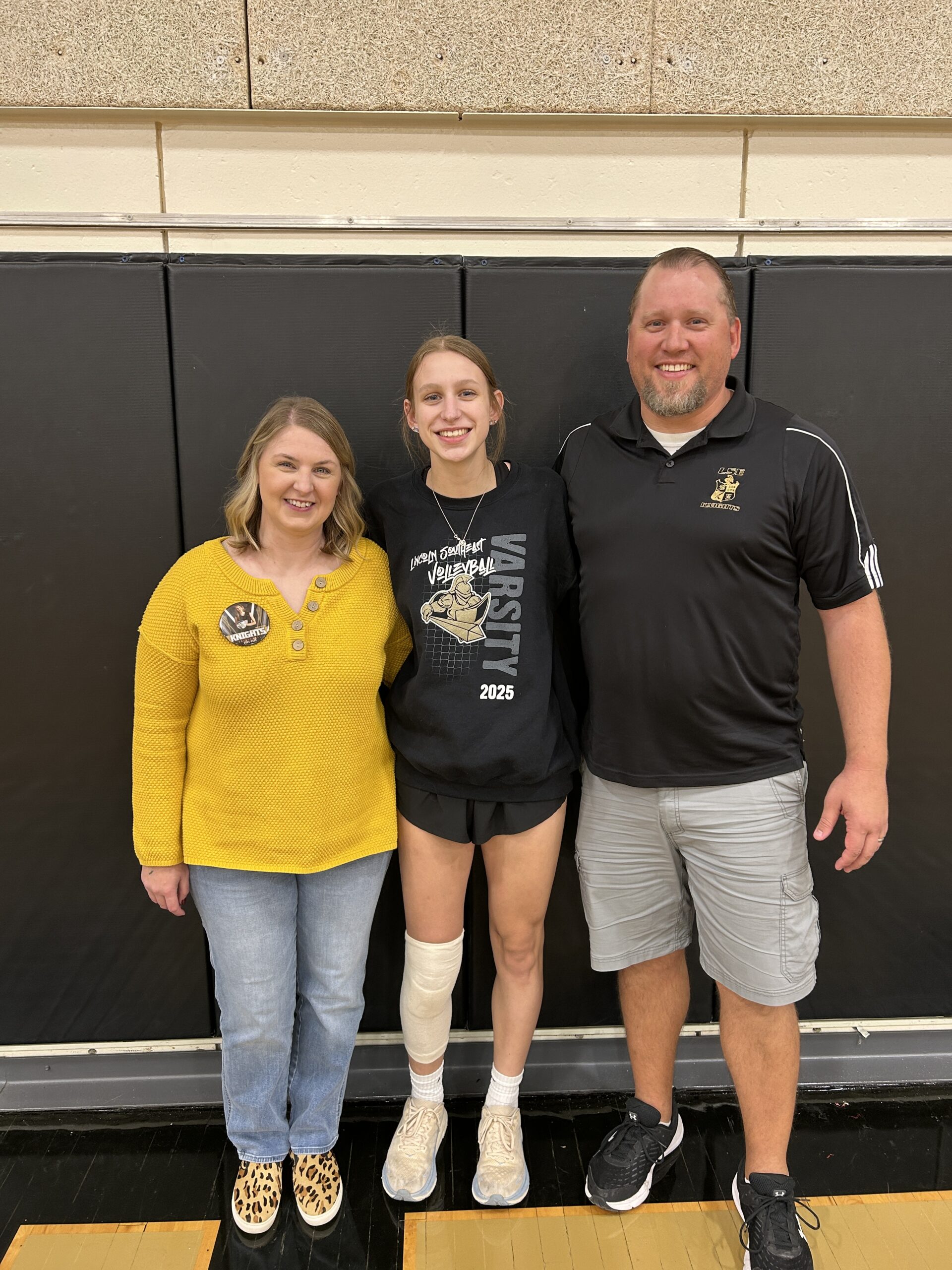 Parents smiling standing with volleyball player