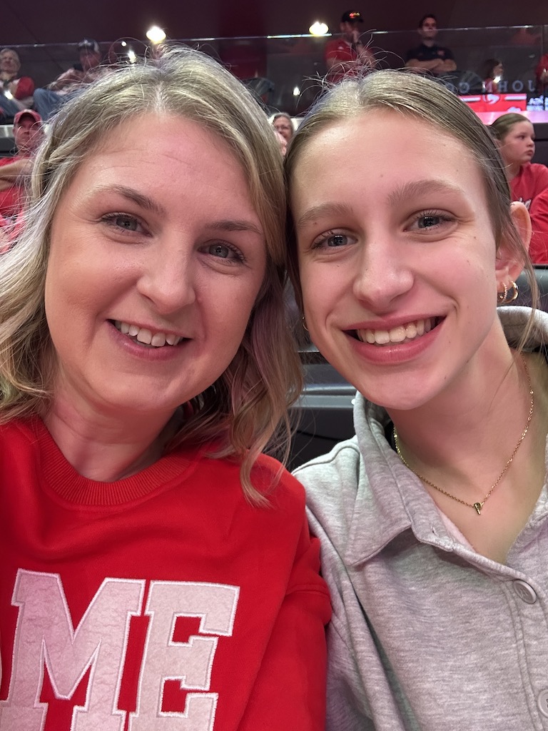 Mom and daughter posing and smiling at at Husker volleyball game