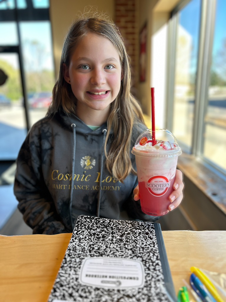 Girl smiling holding smoothie in a coffee shop