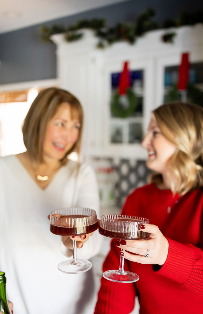 two friends smiling in the background toasting with a festive holiday drink