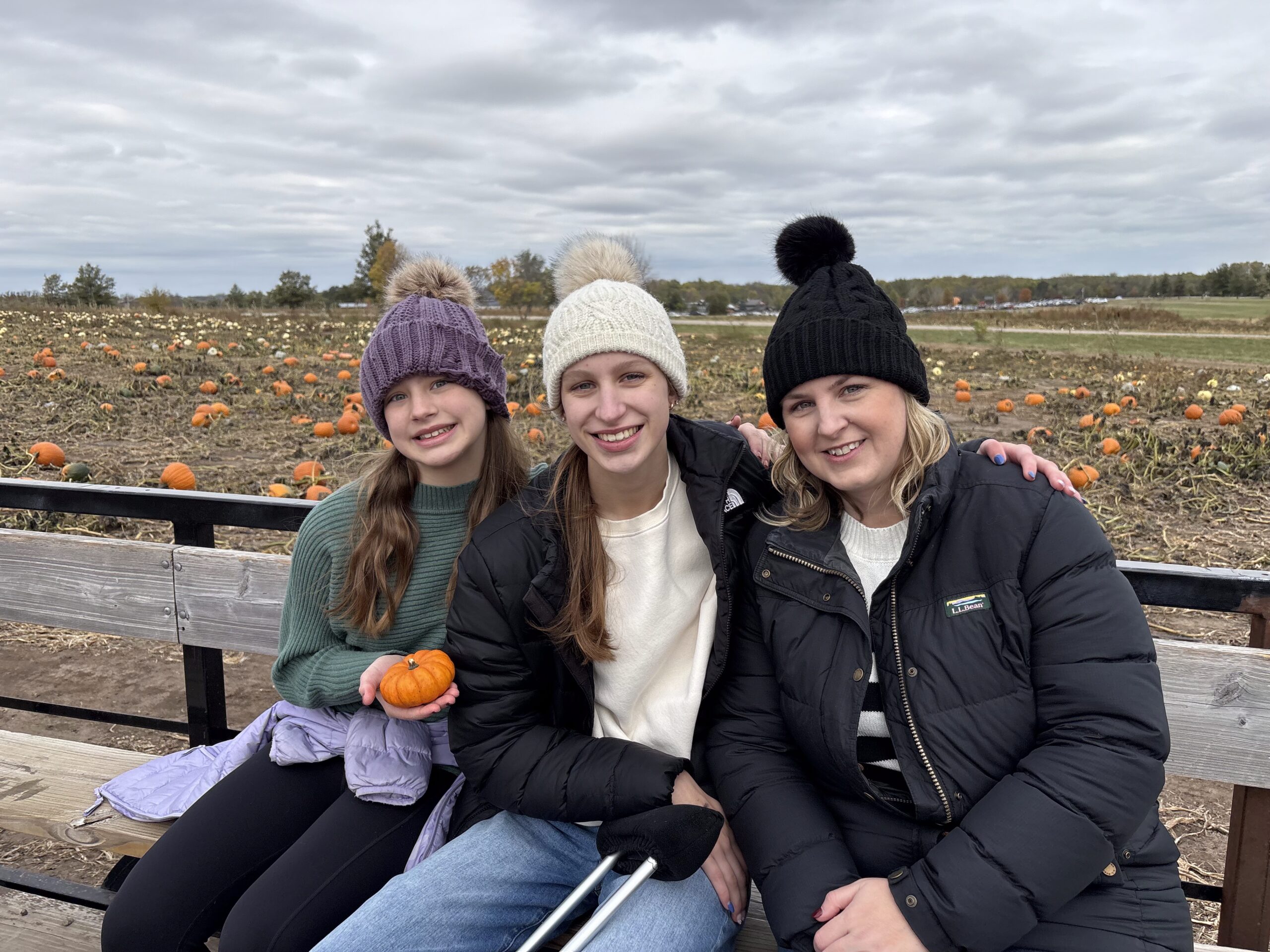 Mother and daughters smiling on a hayrack ride at the pumpkin patch