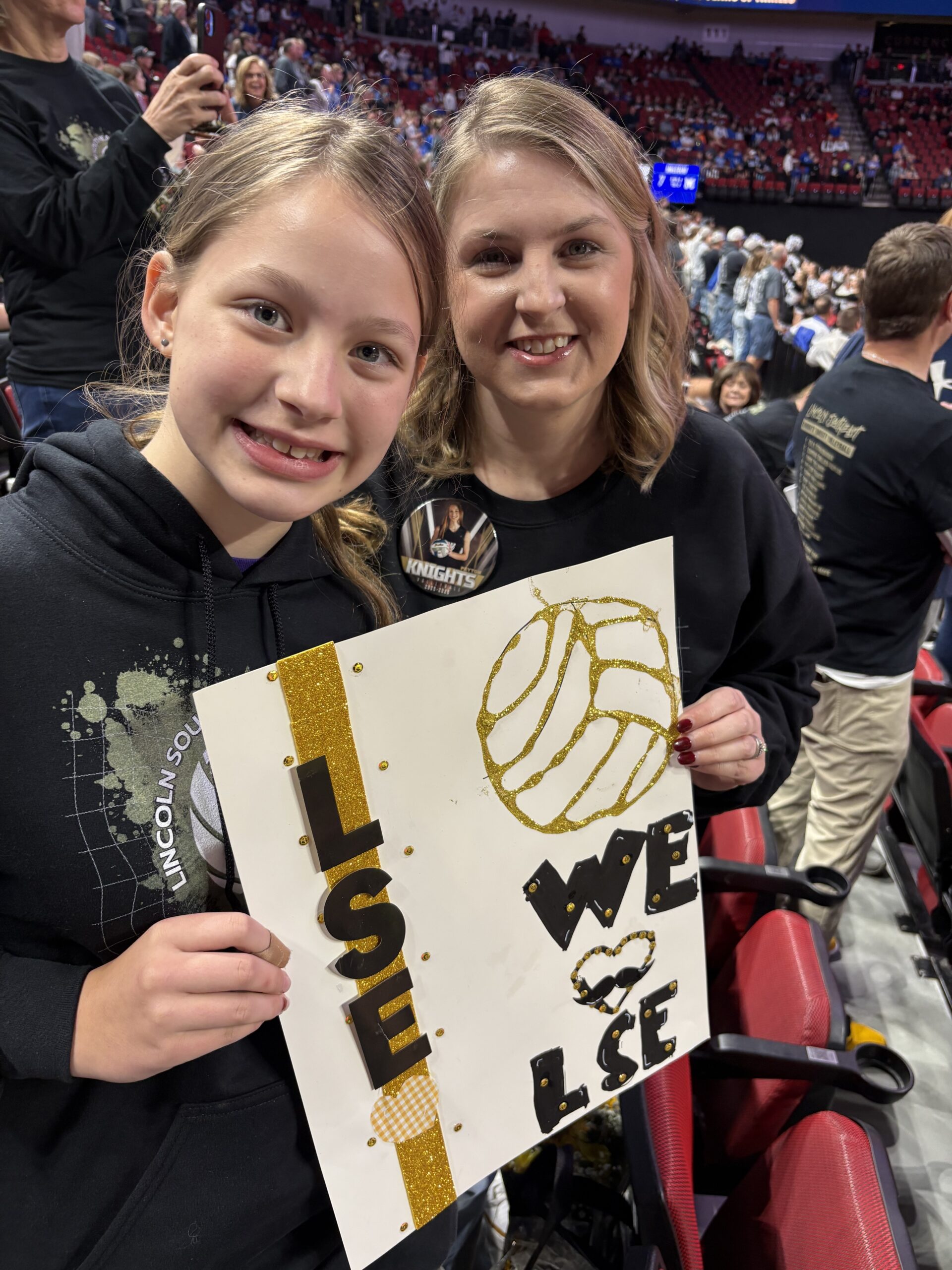 mom and daugter holiding a poster cheering at the state volleyball tournament