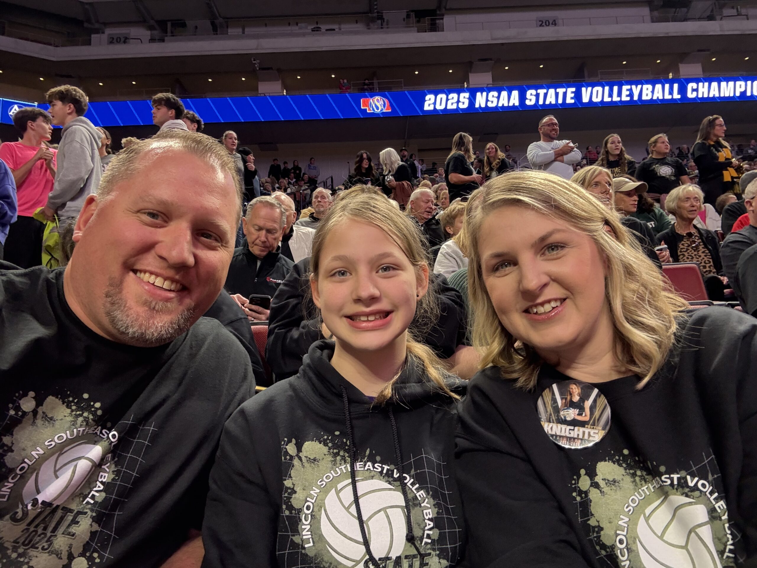 Smiling family sitting in the stands at the state volleyball tournament