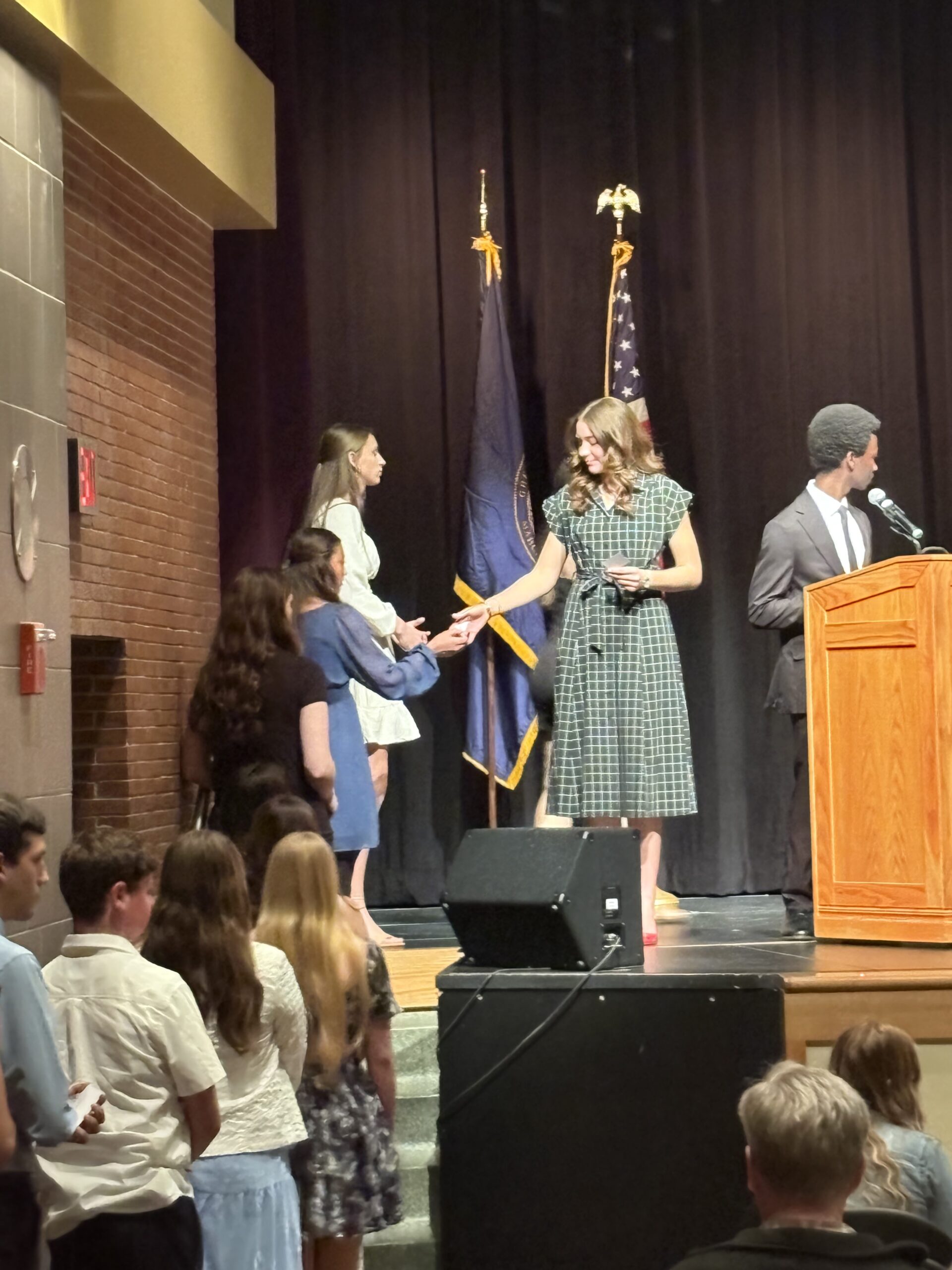 girl walking across the stage at a national honor socieety indcution ceremony