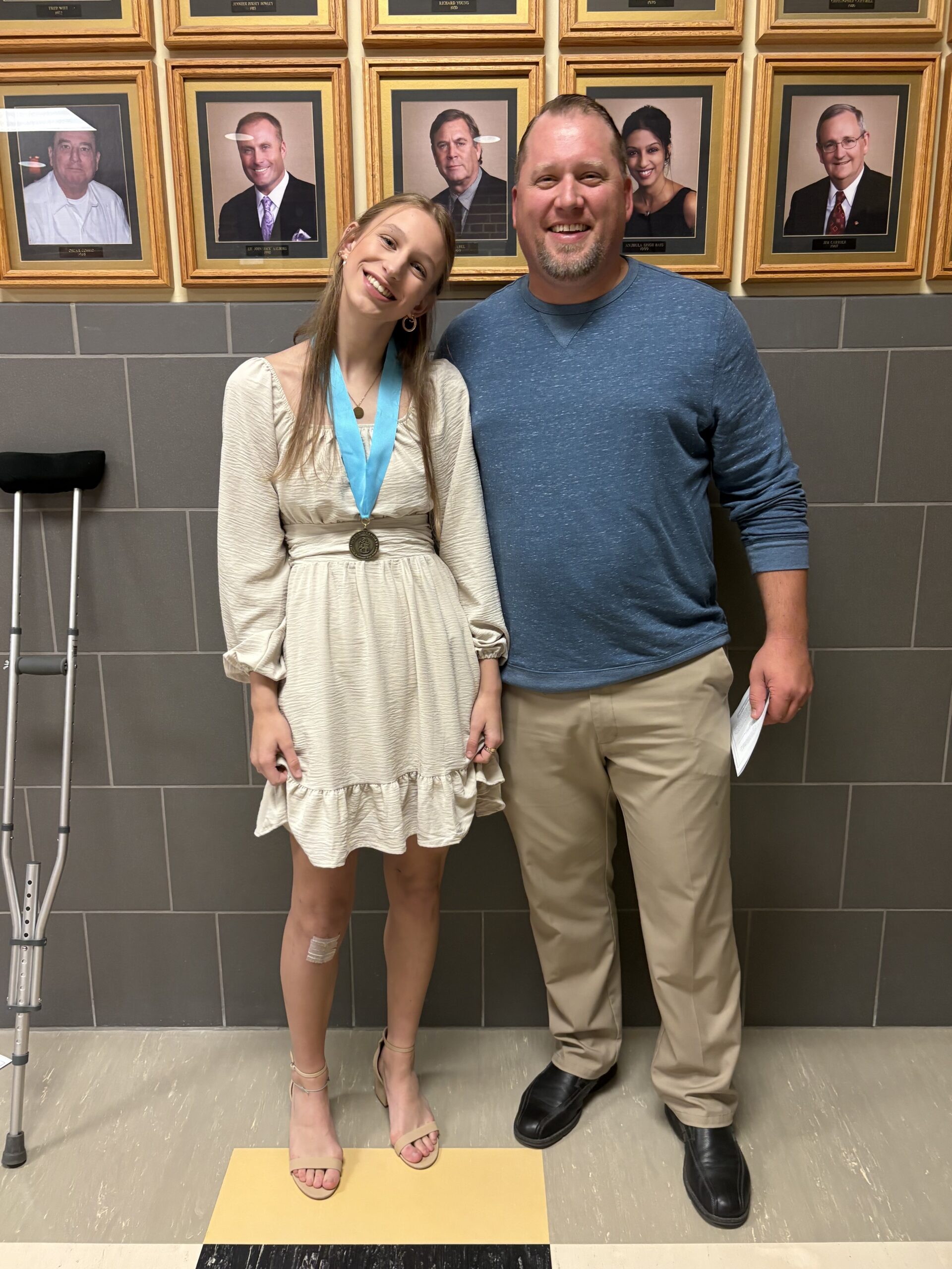 girl standing with her dad smiling with her natinal honor society medal