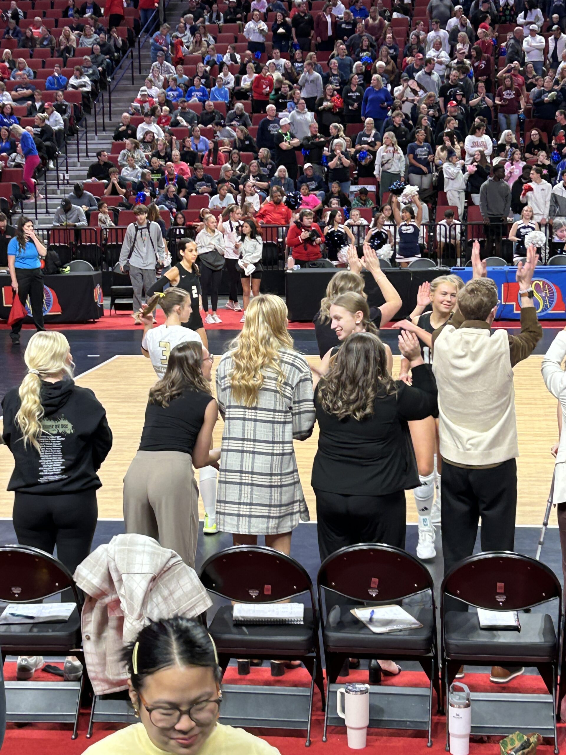 a volleyball player walkign off the court and high fiving her coaches