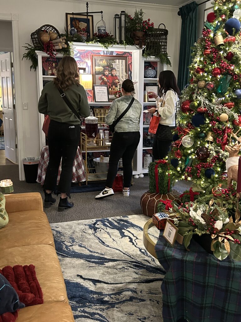 Living room decorated for Christmas with people grabbing drinks for the bar station set up for a holiday party