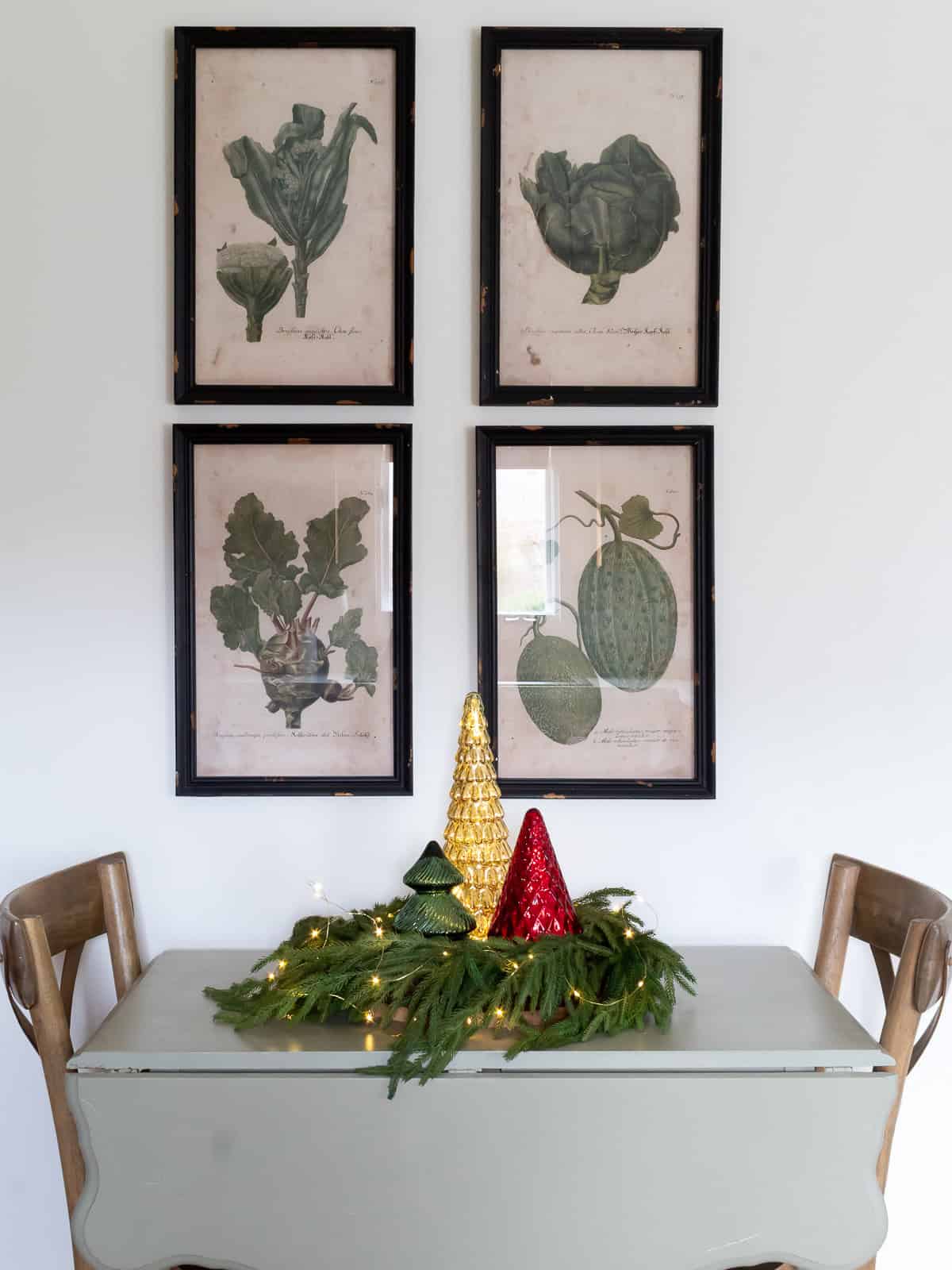 small eat-in table in the kitchen with traditional christmas decor including a wreath, twinke lights, and 3 mercrury glass Christmas trees