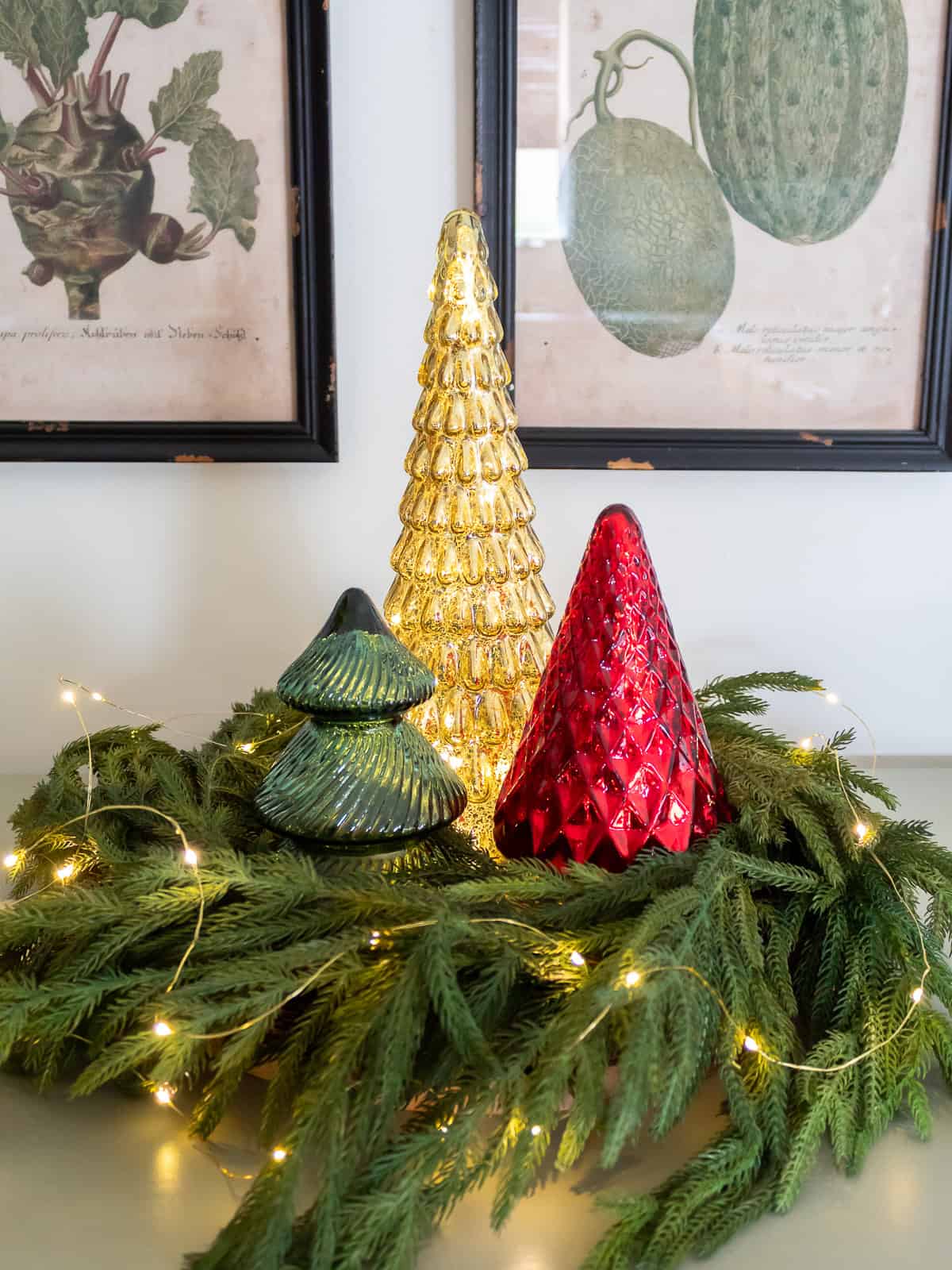 Mercury glass Christmas trees in gold, red, and green displayed inside a fresh greenery wreath with twinkle lights, creating a classic centerpiece that fits traditional Christmas decorating ideas and a cozy Ralph Lauren Christmas style.