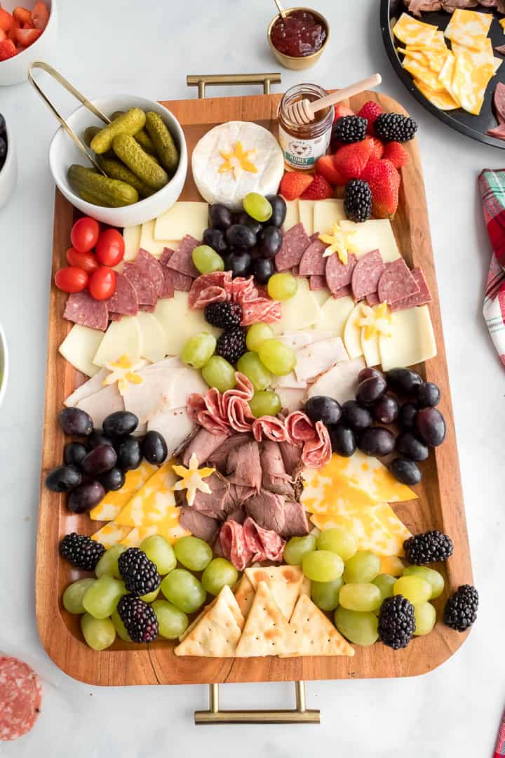 Finished Christmas tree charcuterie board with meat, cheese, fresh fruit and fresh rosemary garnish