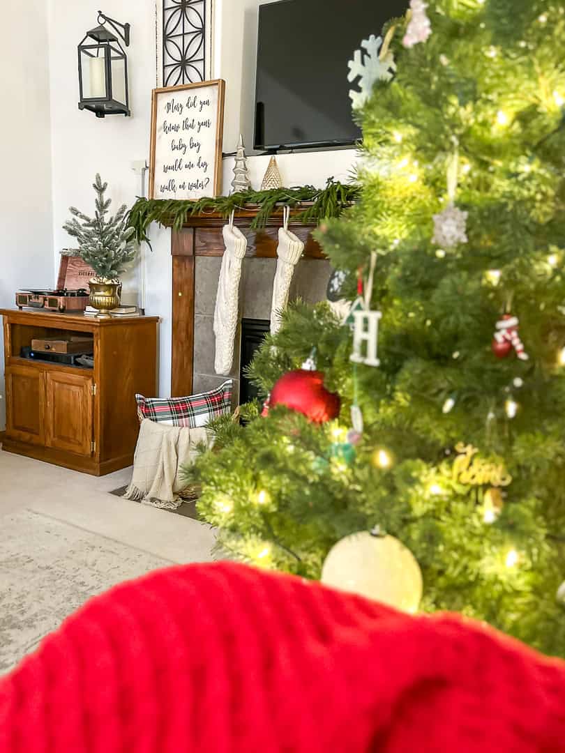 Christmas fireplace mantel with stockings and garland and a tree in the foreground
