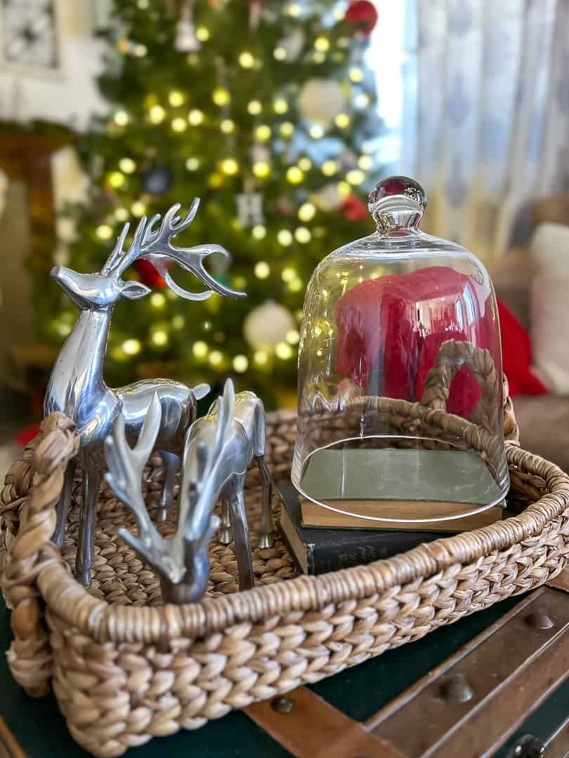 Christmas vignette with reindeer and a class cloche styled in a tray on top of a coffee tabe with a Christmas tree in the background