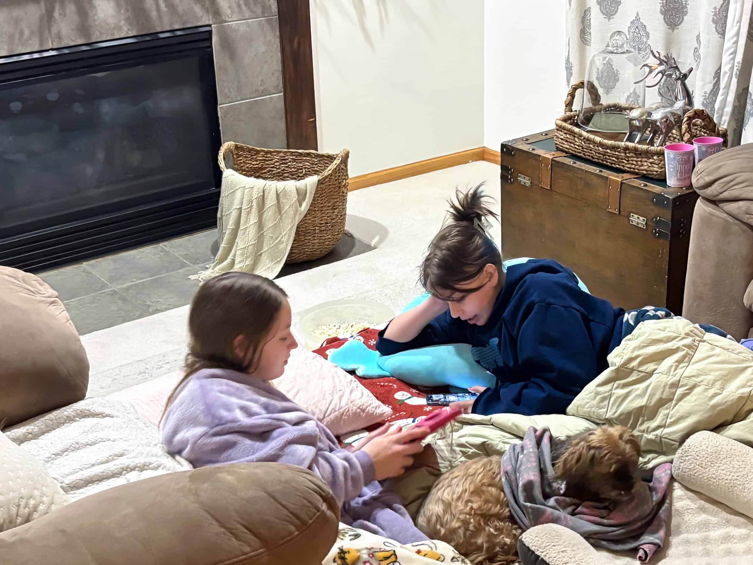 two friends hanging out on the living room floor playing video games and snuggling a dog