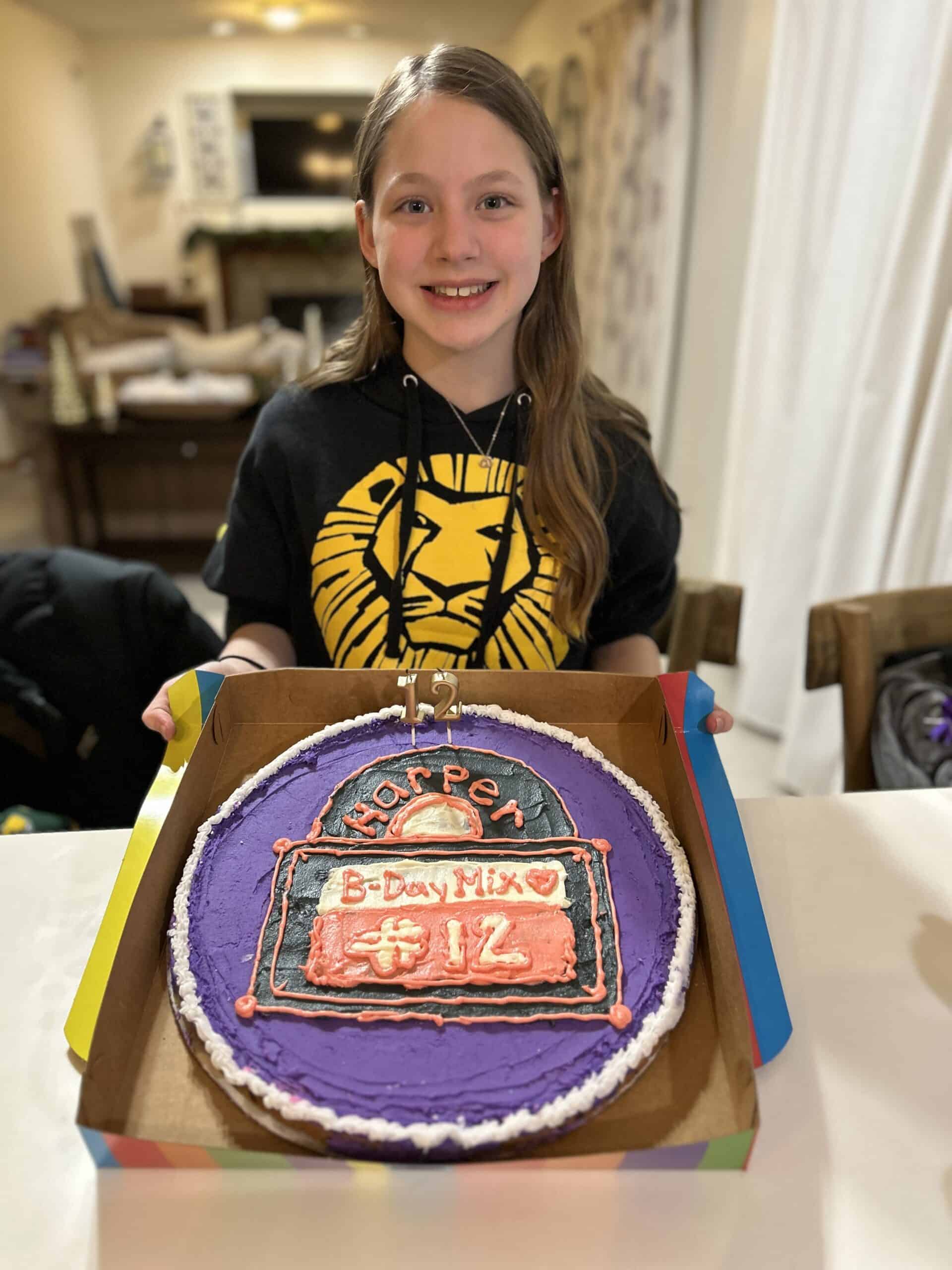 girls miling and holding up a cookie cake for her birthday
