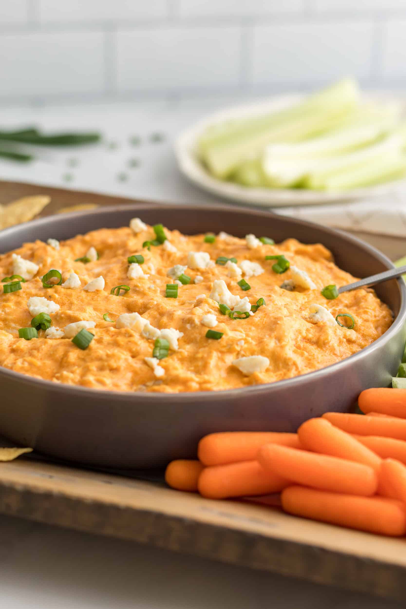 Crockpot buffalo chicken dip served in a bowl with celery sticks and carrots on the side