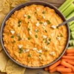 Overhead view of crockpot buffalo chicken dip served with tortilla chips, celery, and carrots