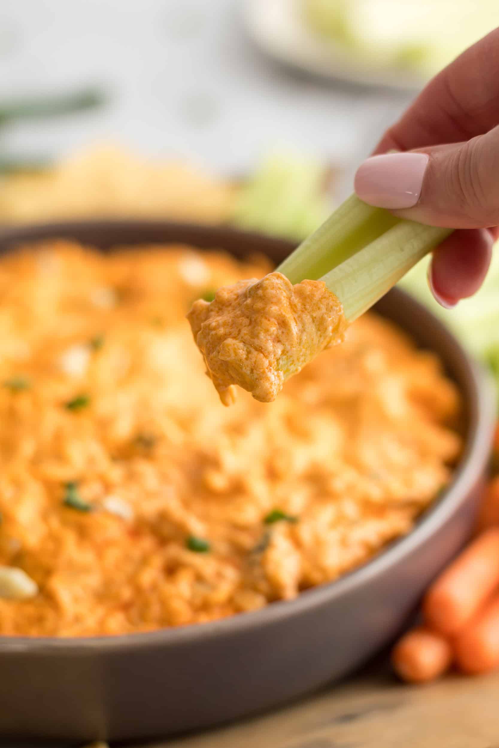 Celery stick dipped into creamy crockpot buffalo chicken dip