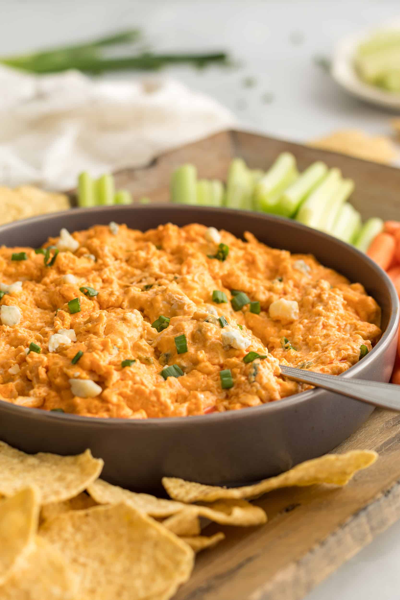 Side view of crockpot buffalo chicken dip served with tortilla chips and vegetables