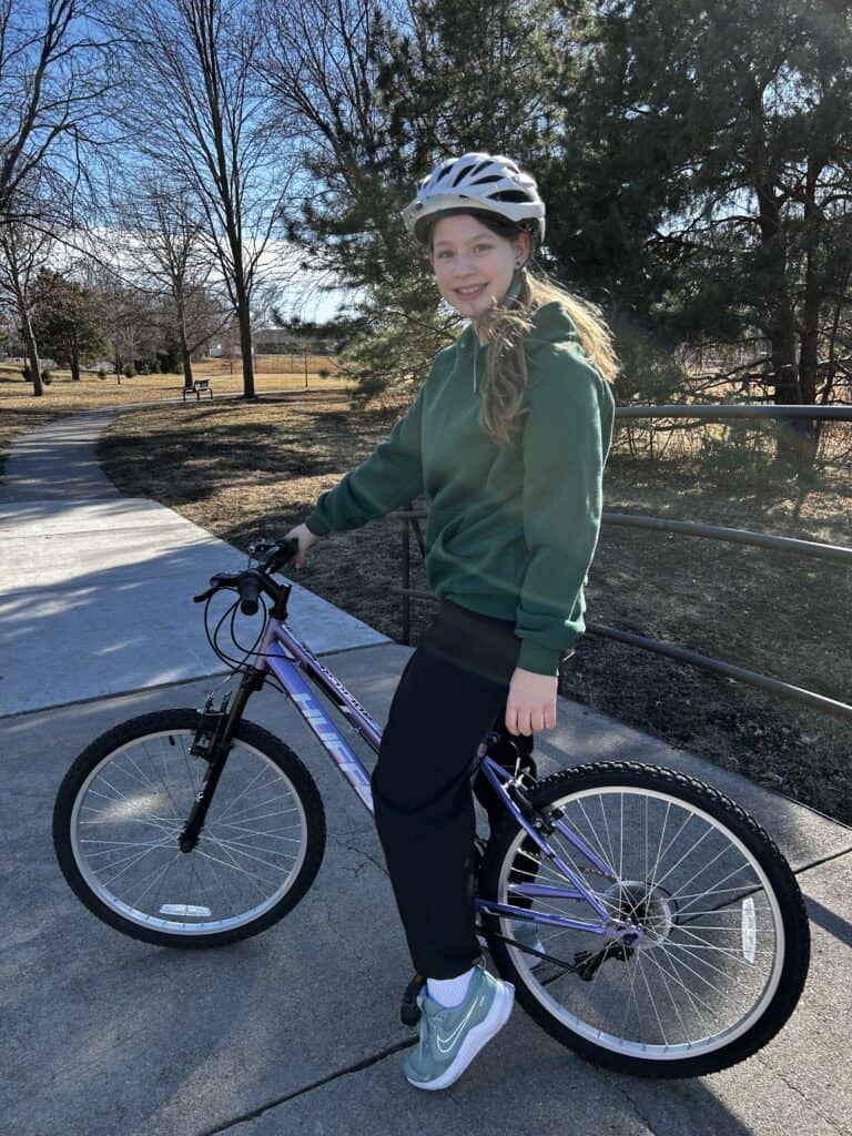 Girl smiling and riding her bike at the park