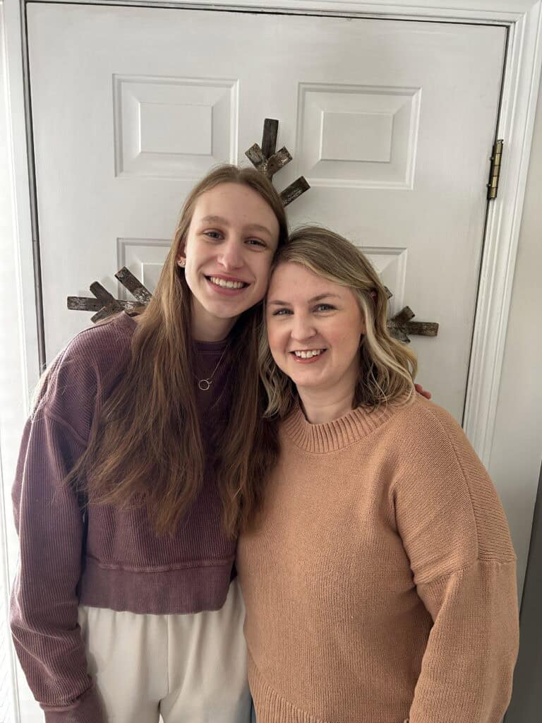 Girl and mom hugging and smiling standing in front of a door