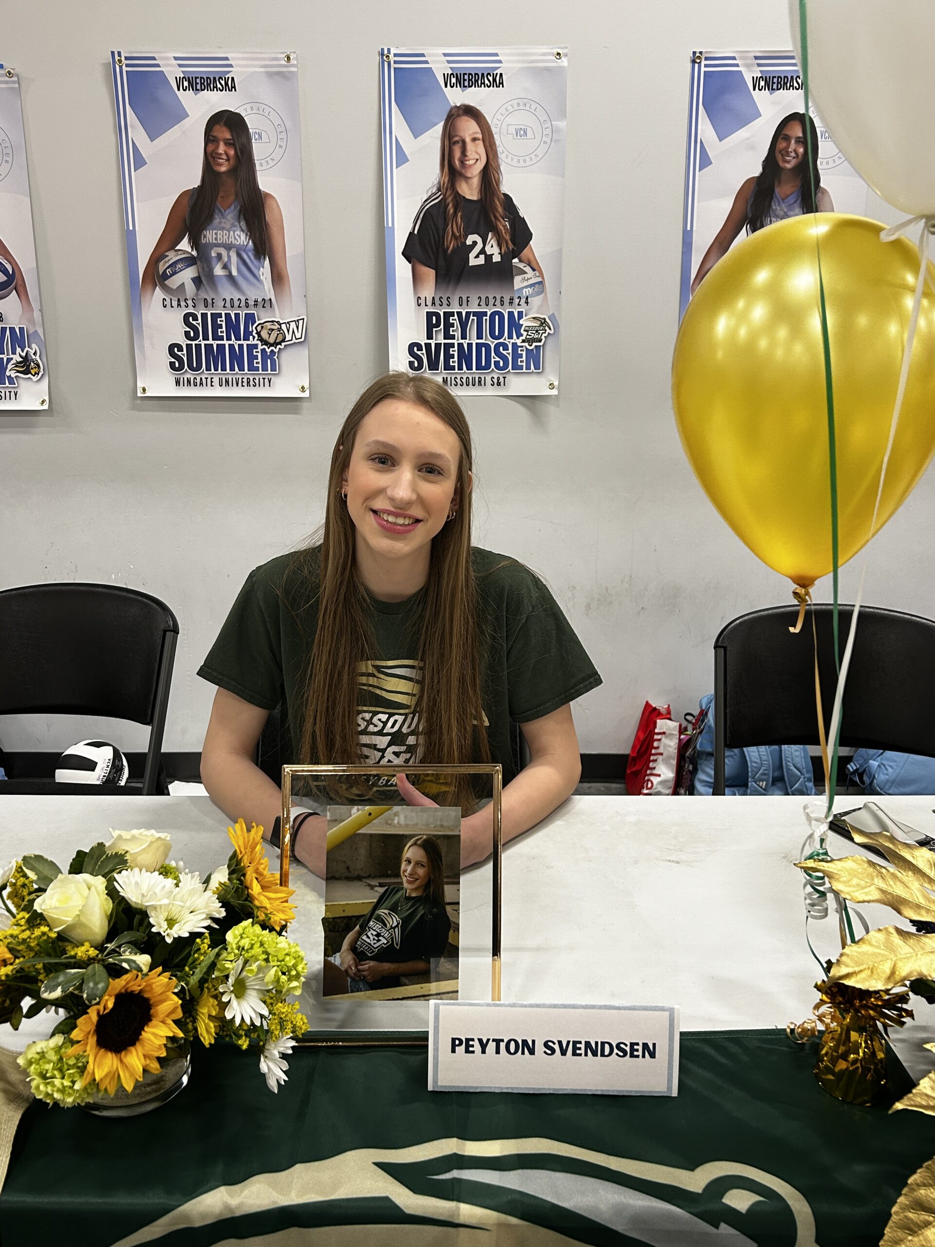 Girl smiling seated at a table for a college signing day celebration