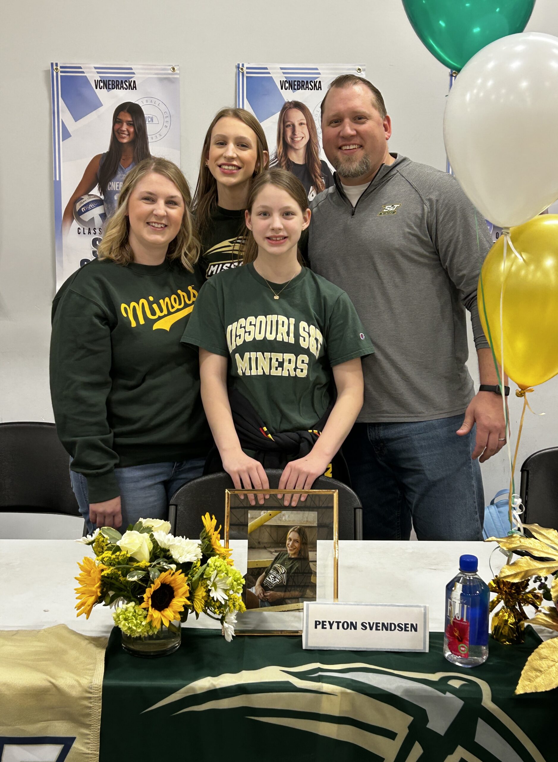 Family standing and smiling at a college volleyball signing day celebration
