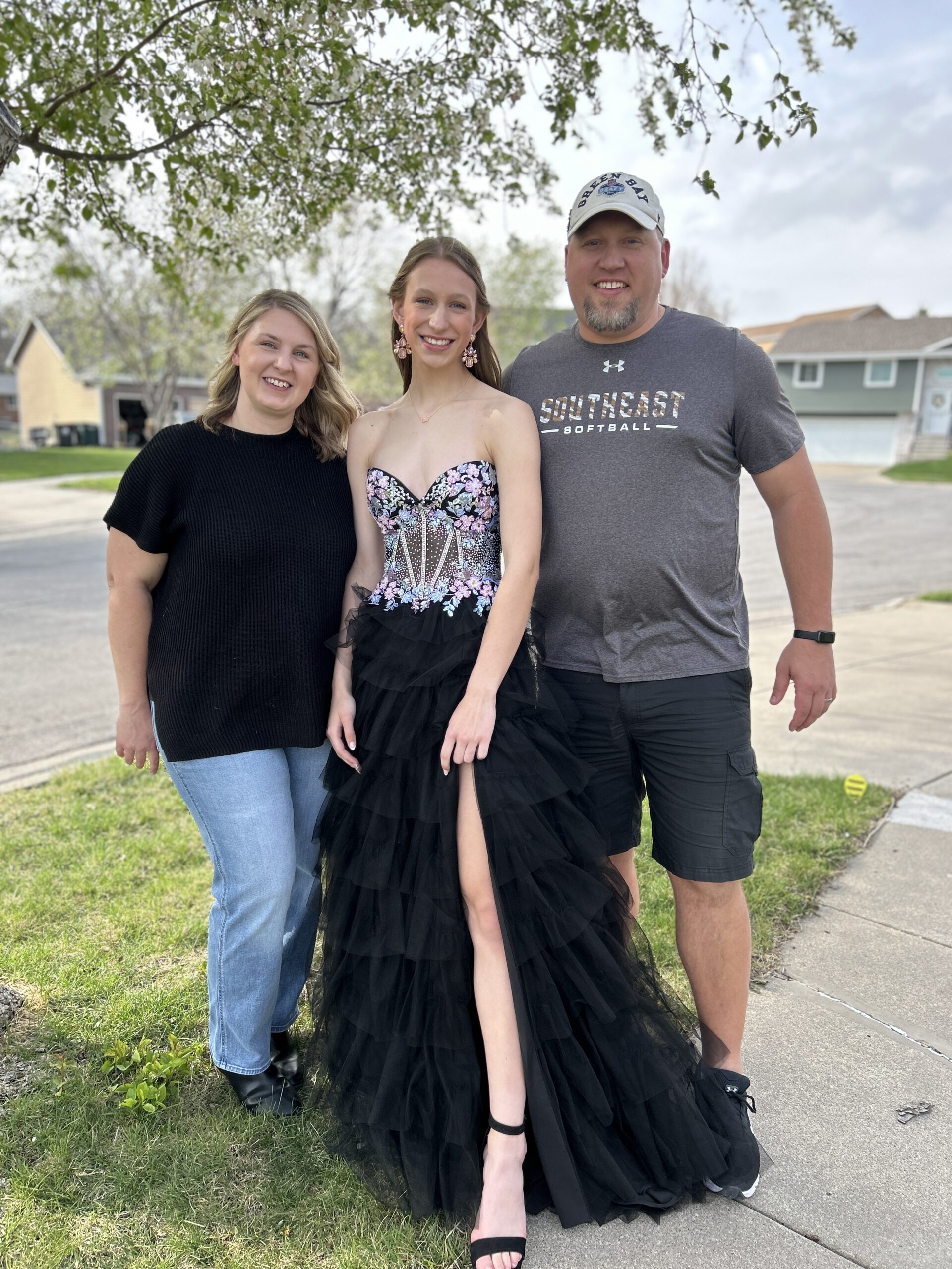 Parents posting for a photos with their daughter before prom