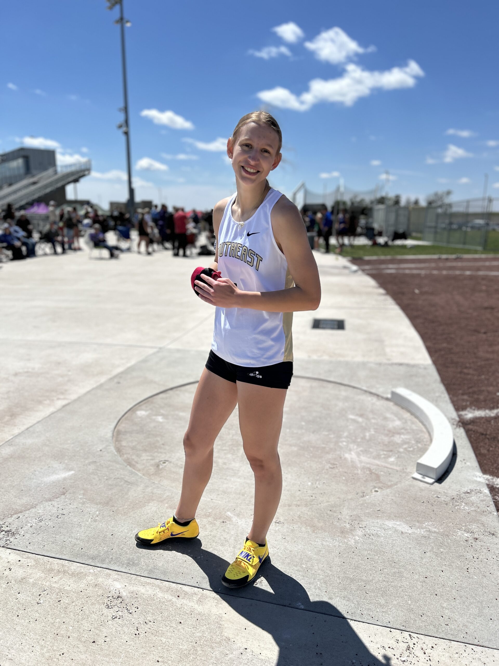Athlete standing in a track uniform and smiling before throwing the shot put
