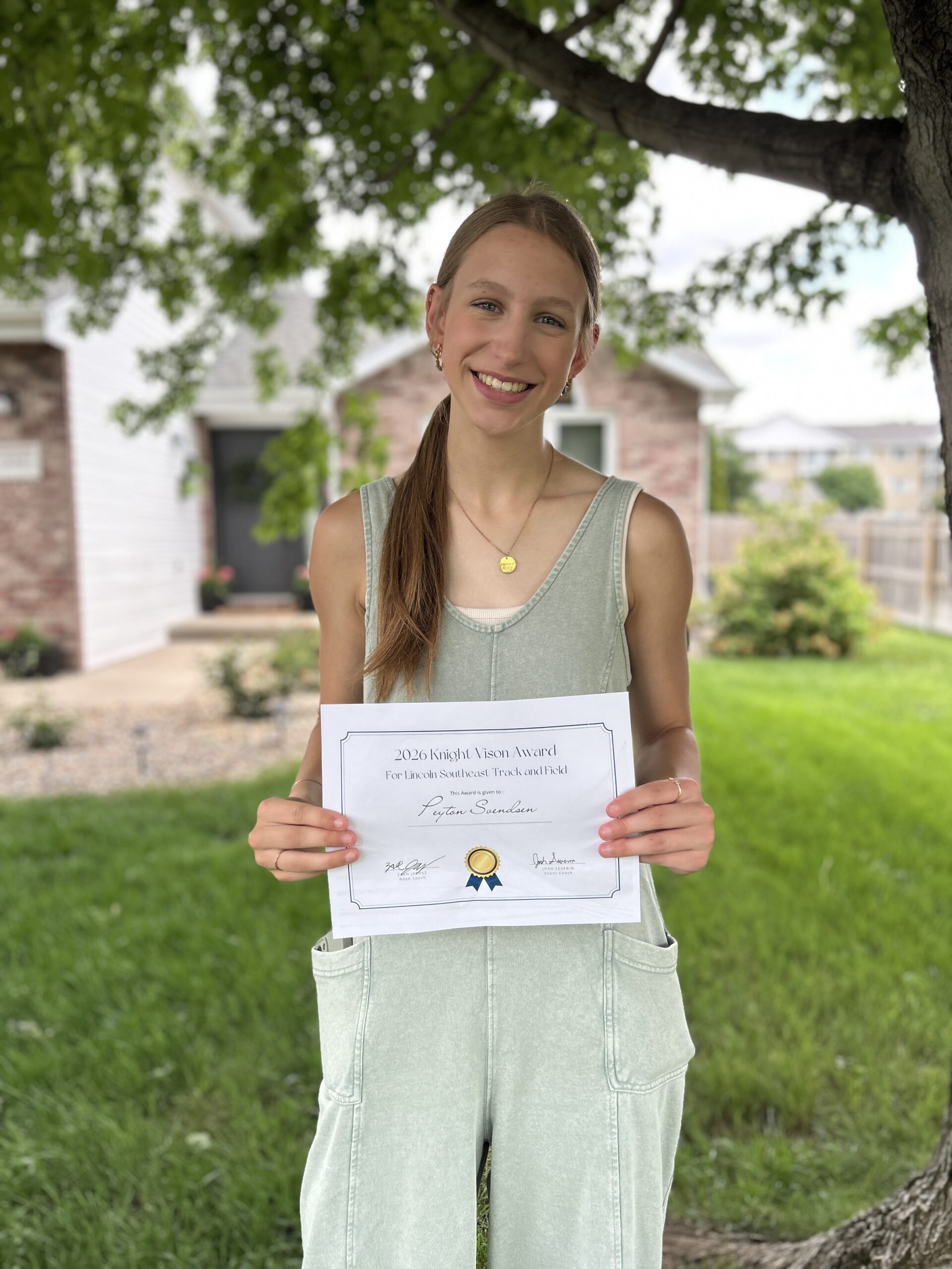 Girl standing and smiling with a special certificate for positivity at the end of track awards banquet