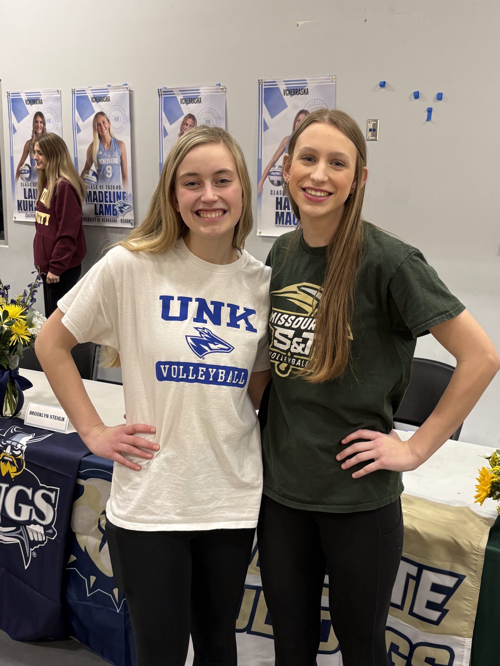 Friends and club volleyball teammates standing and smiling at a signing day celebration