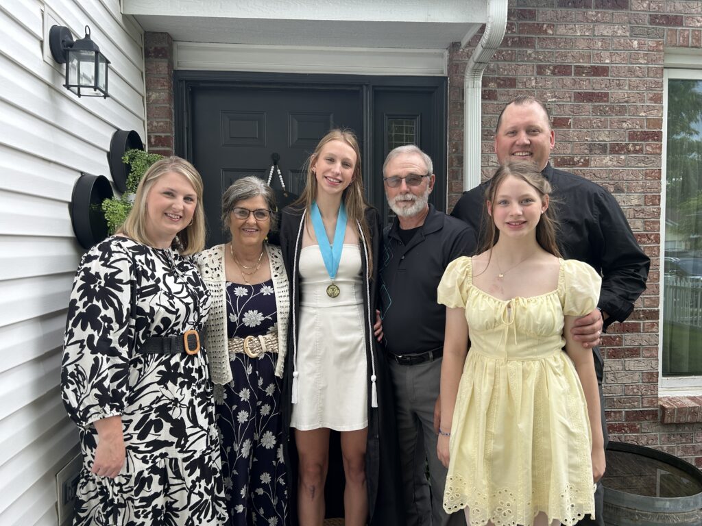 Extended family with grandparents smiling and posing for a photo with the graduate