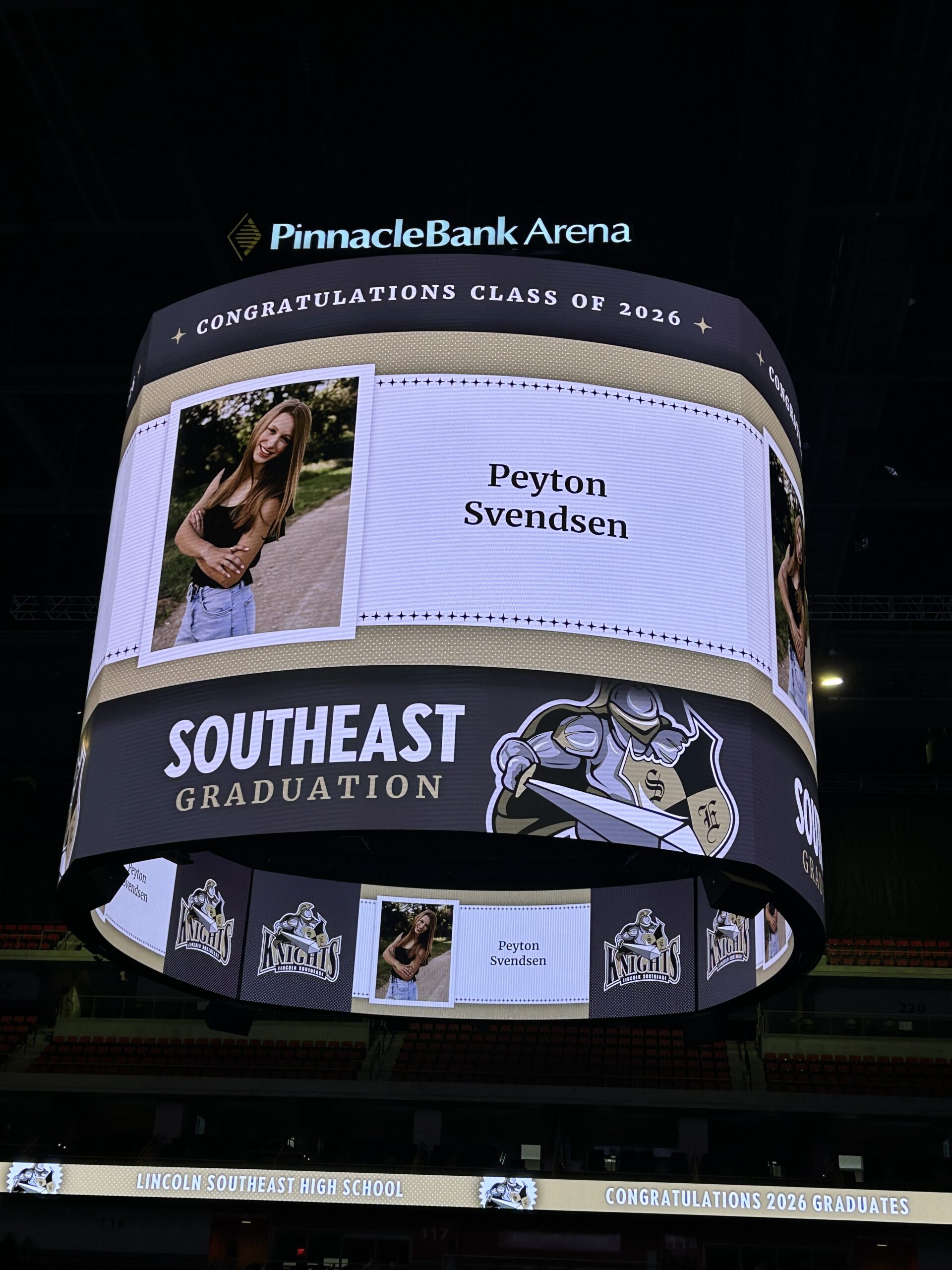Electronic board with graduation photo, name and school displayed above the arena during the ceremony
