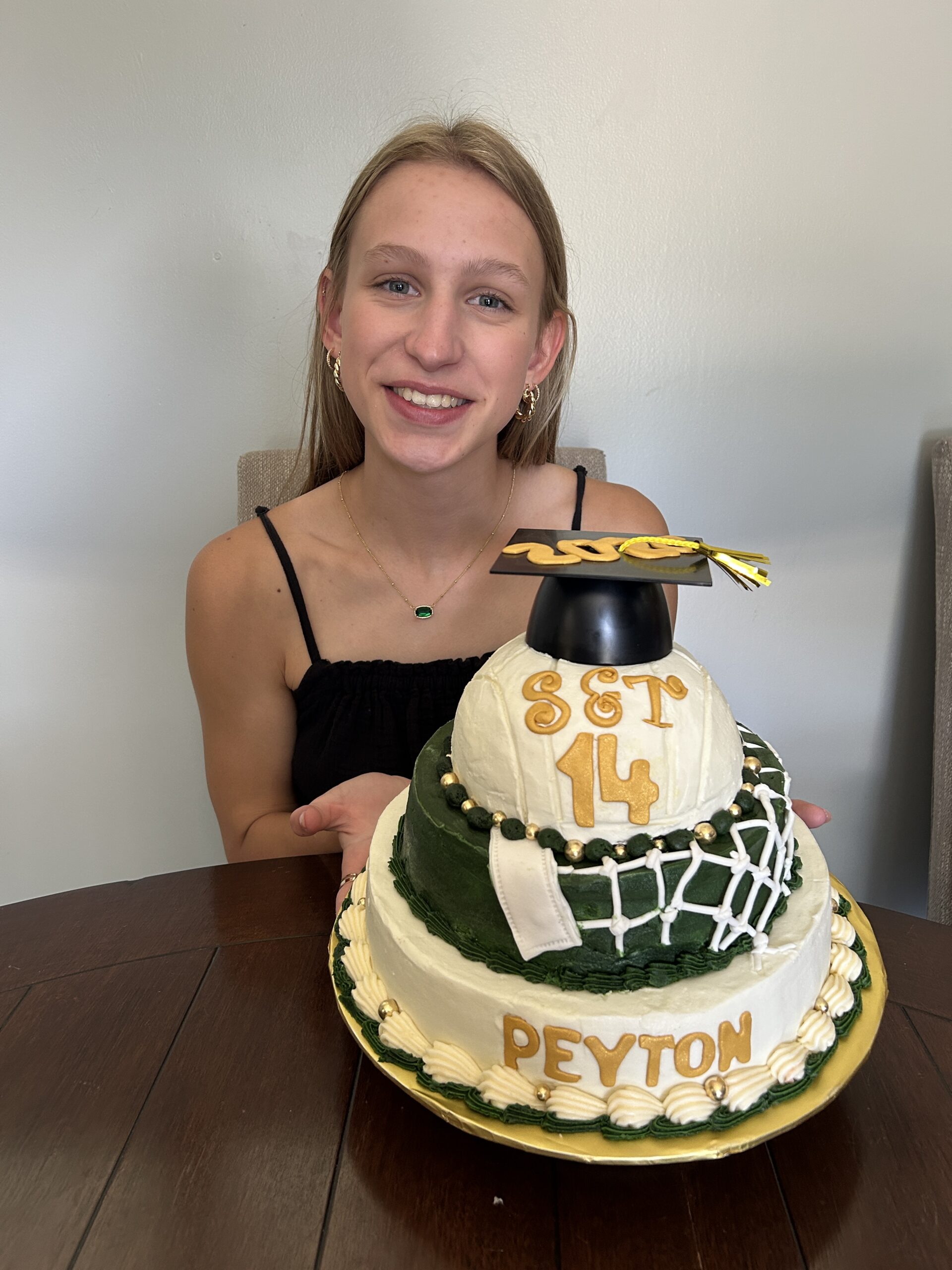 Girl smiling and holding a custom 3-tier volleyball cake for her graduation party