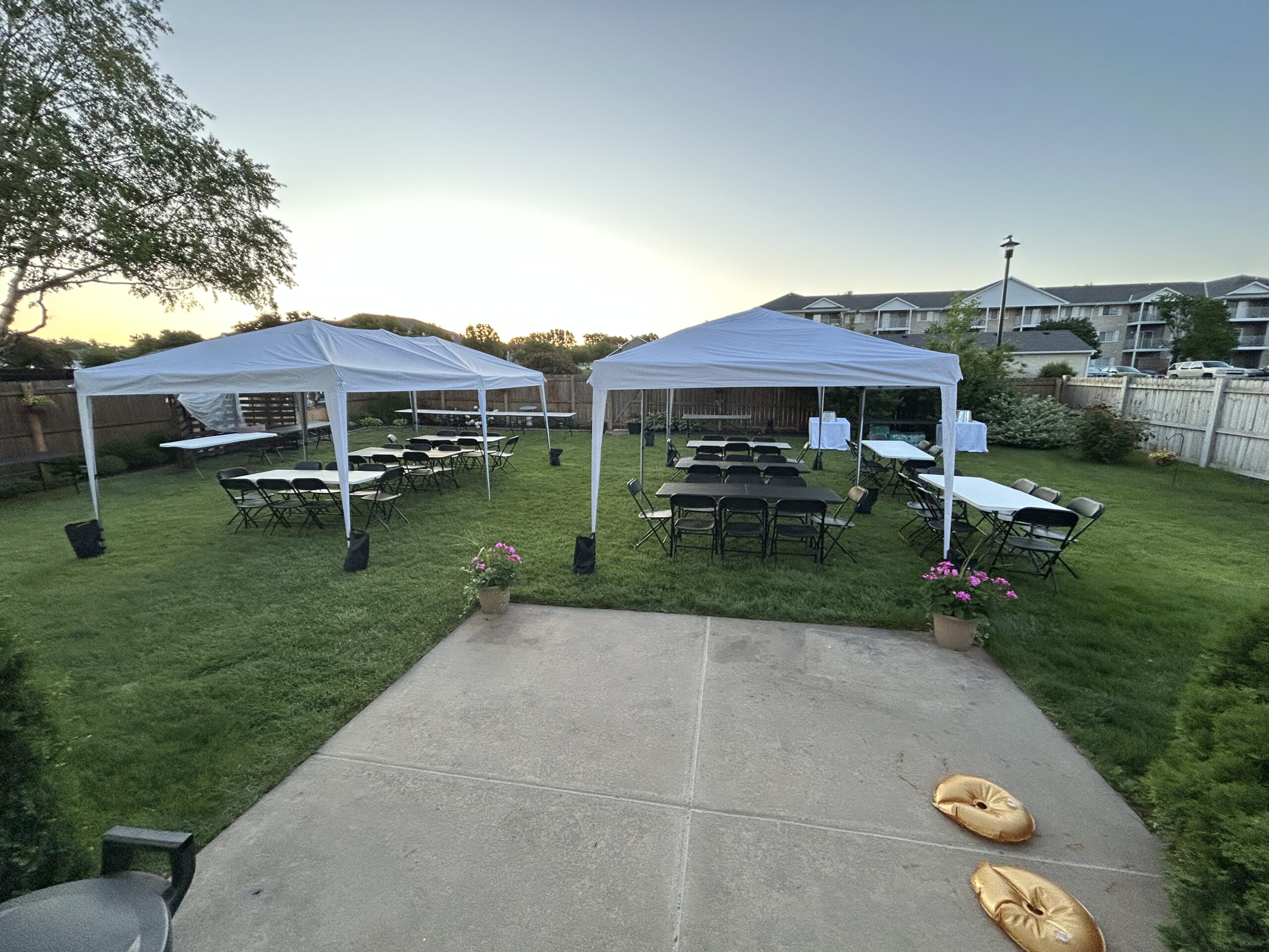 Backyard set up with tents, tables and chairs for a graduation party before fully decorated