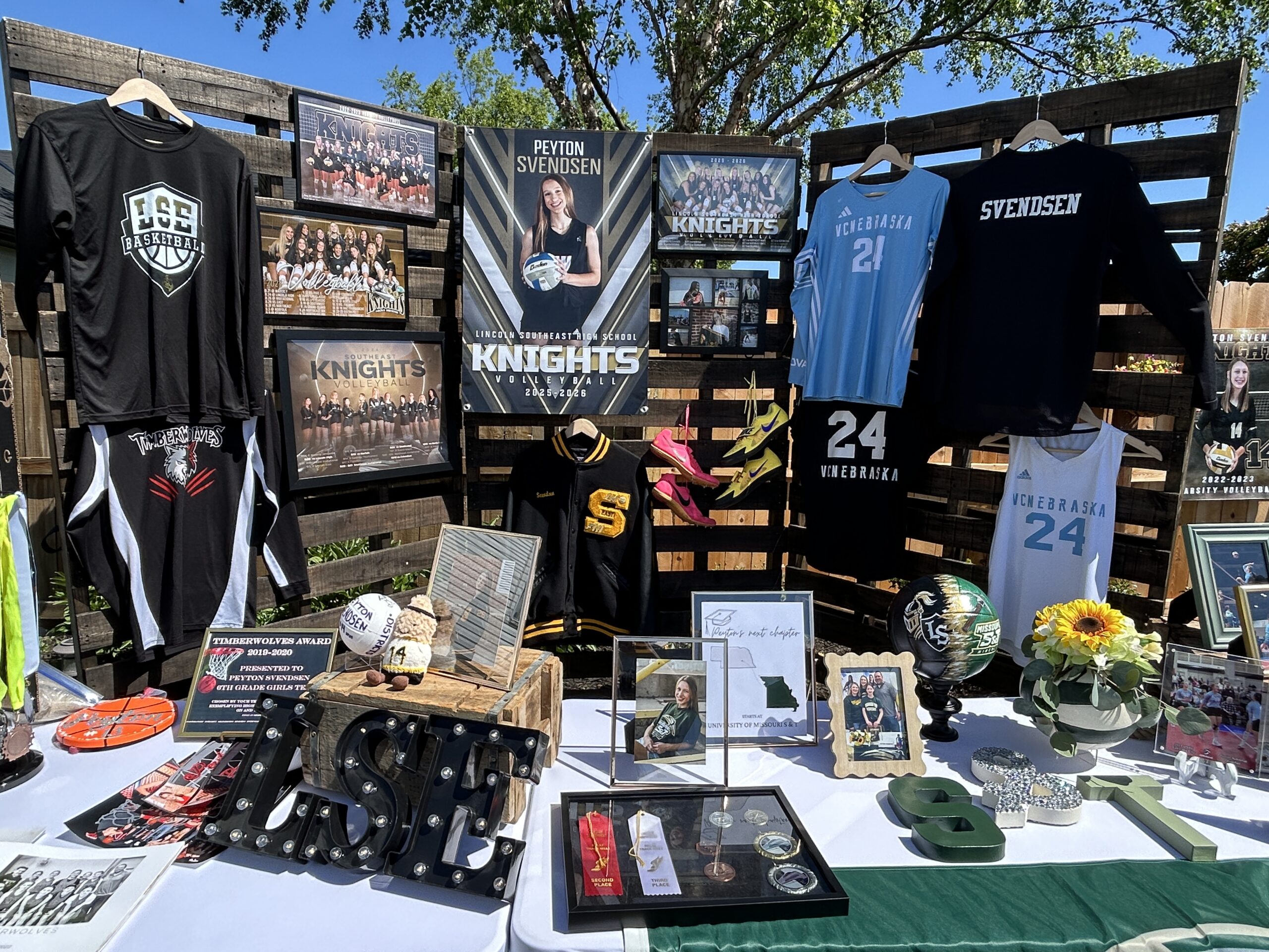 Graduation party table featuring volleyball memorabilia, athletic awards, senior photos, and college-bound decor celebrating a student-athlete.