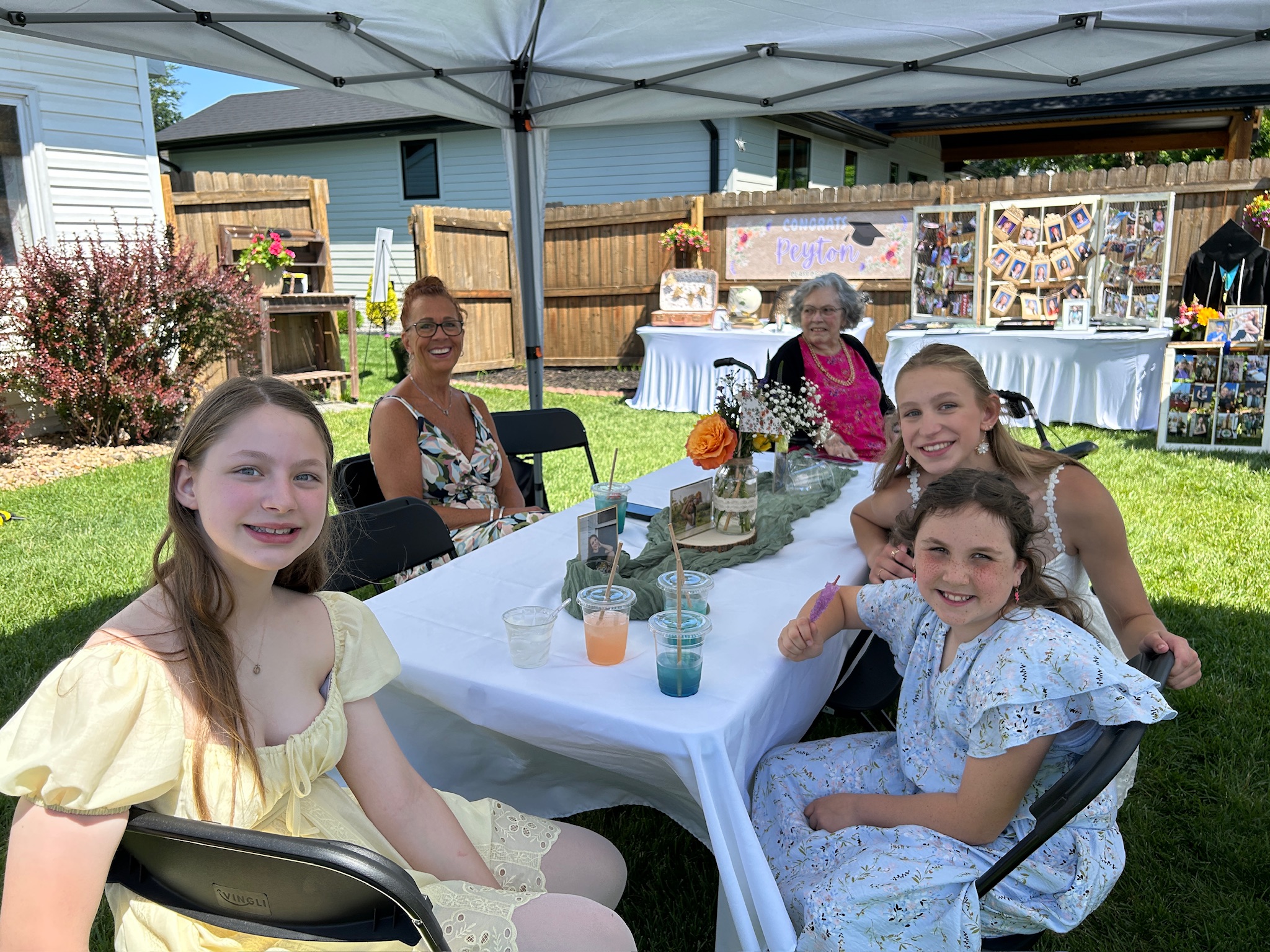 Multi-generational family members seated around a decorated table during a backyard graduation celebration.