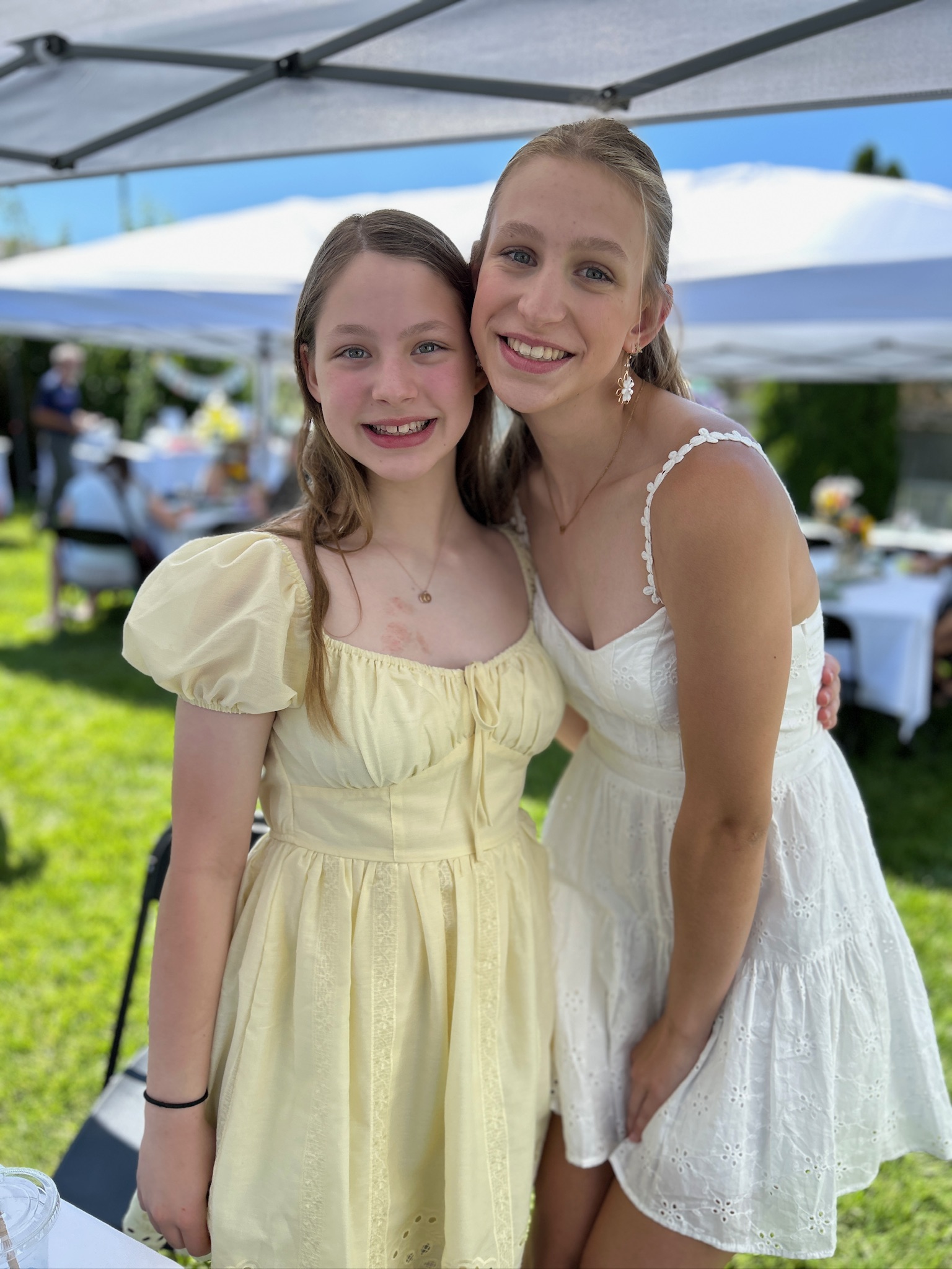 Two sisters smiling together during a backyard graduation party celebration.