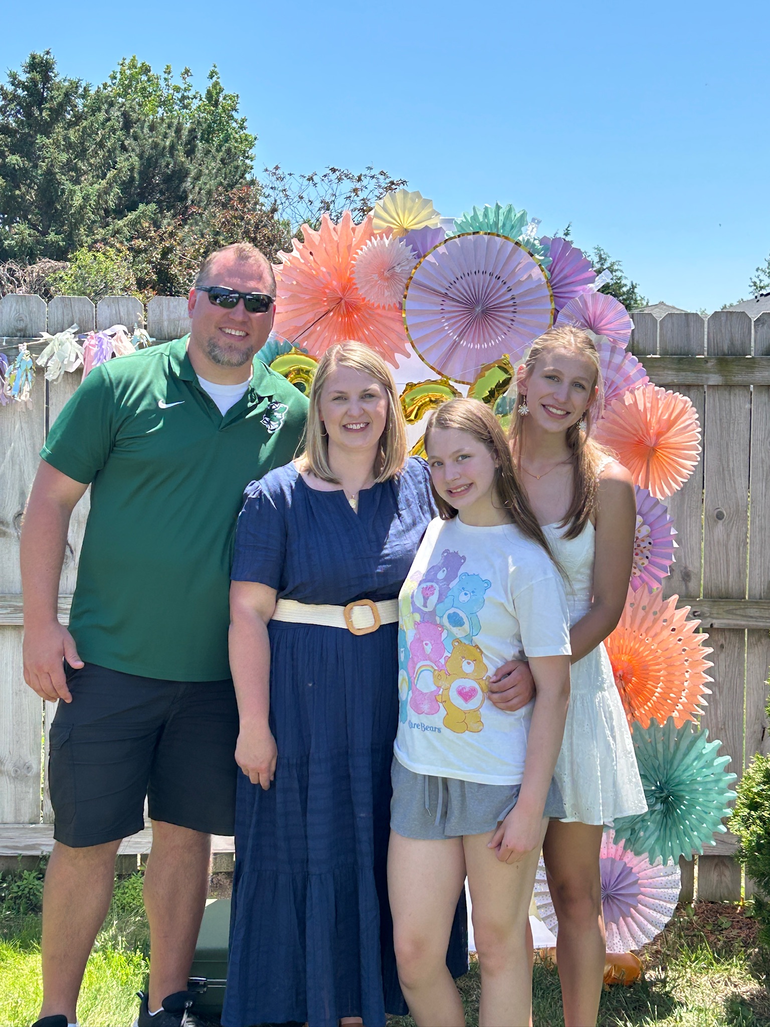 Family portrait in front of a pastel graduation photo backdrop with paper fans and 2026 balloons.