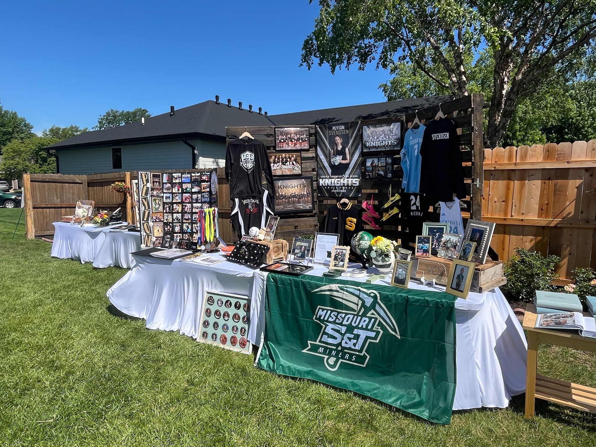 Sports-themed graduation party display showcasing volleyball jerseys, letter jacket, team photos, medals, awards, and senior banners.
