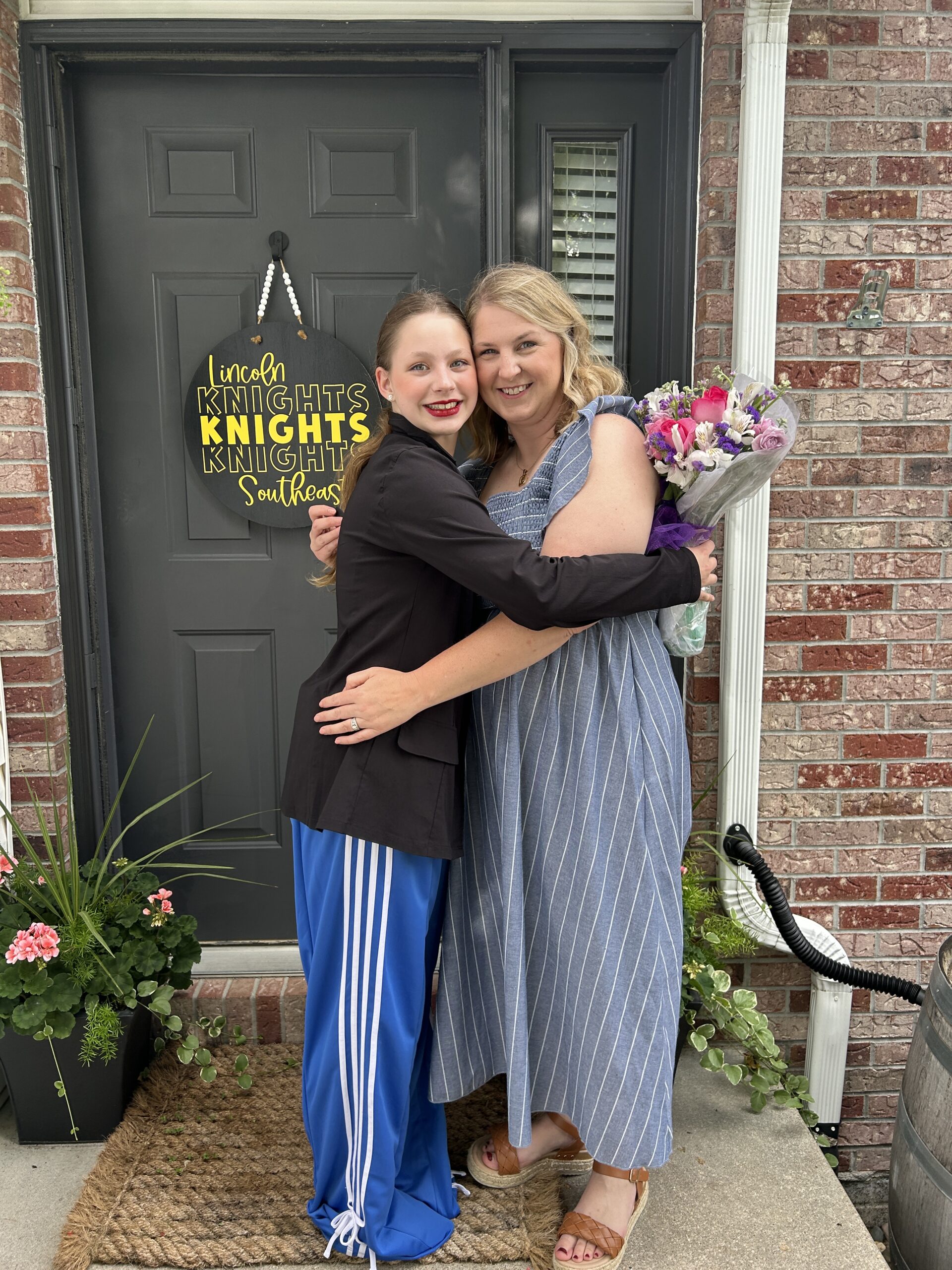 Mother and daughter smilinig and hugging while holding a bouquet of flowers after a dance recital