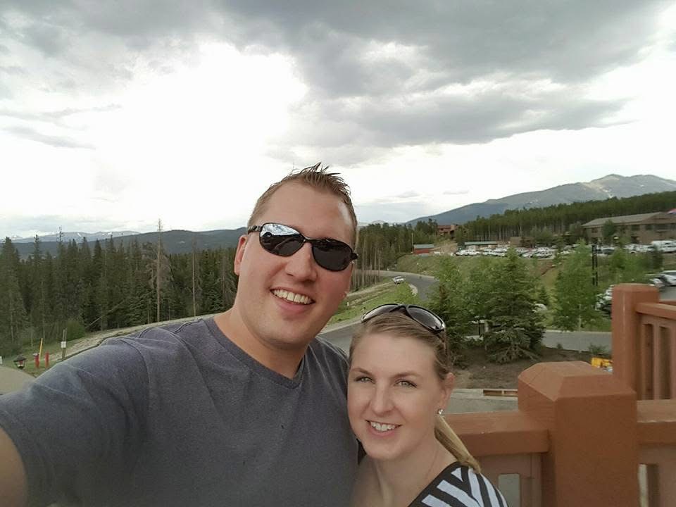 Couple smiling on trip to Colorado with a view of the mountains in th background