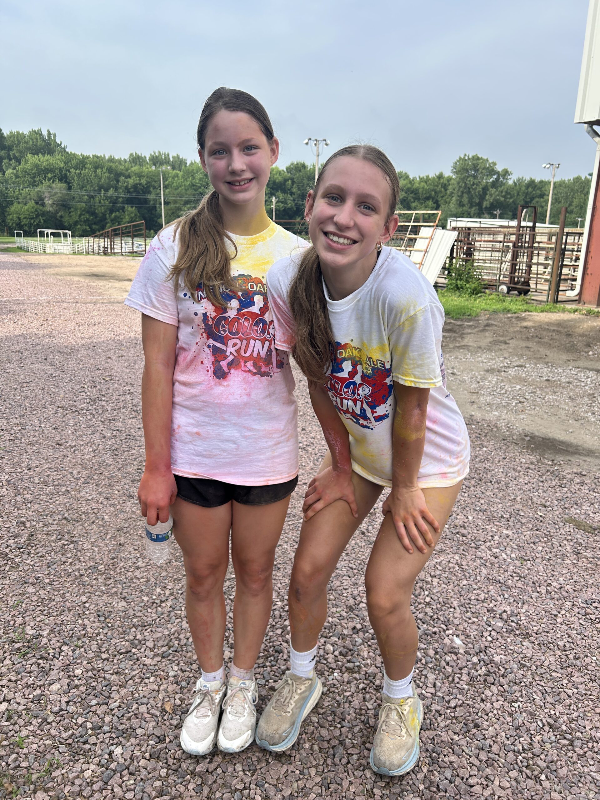 Two girls standing and smiling posing for a photo after a 5k color run