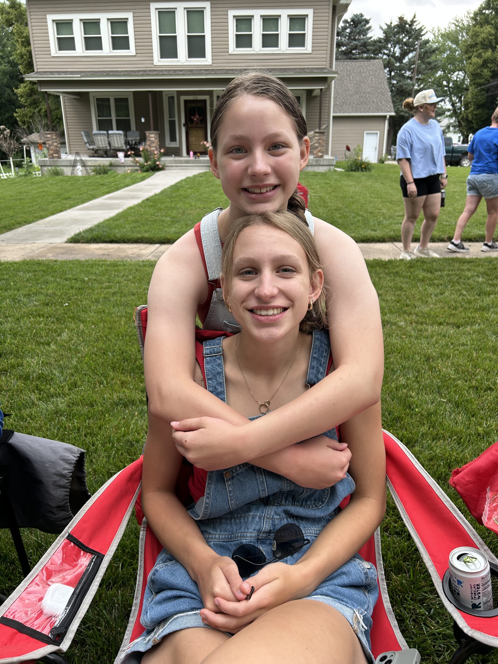Sisters hugghing and smiling at a 4th of July parade